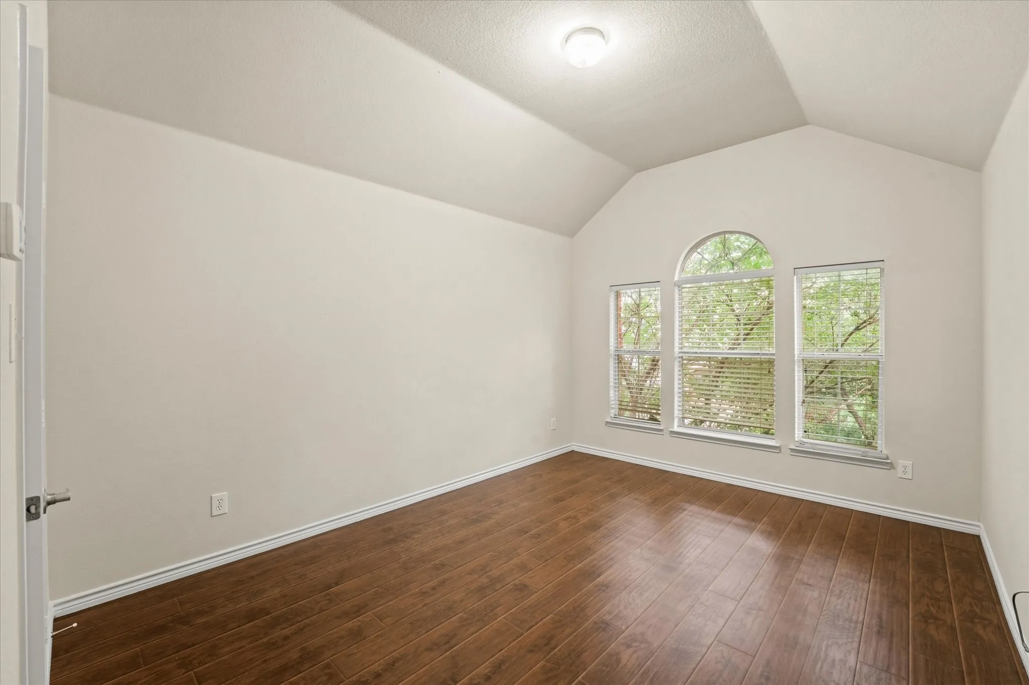 Empty room with lofted ceiling and hardwood / wood-style flooring