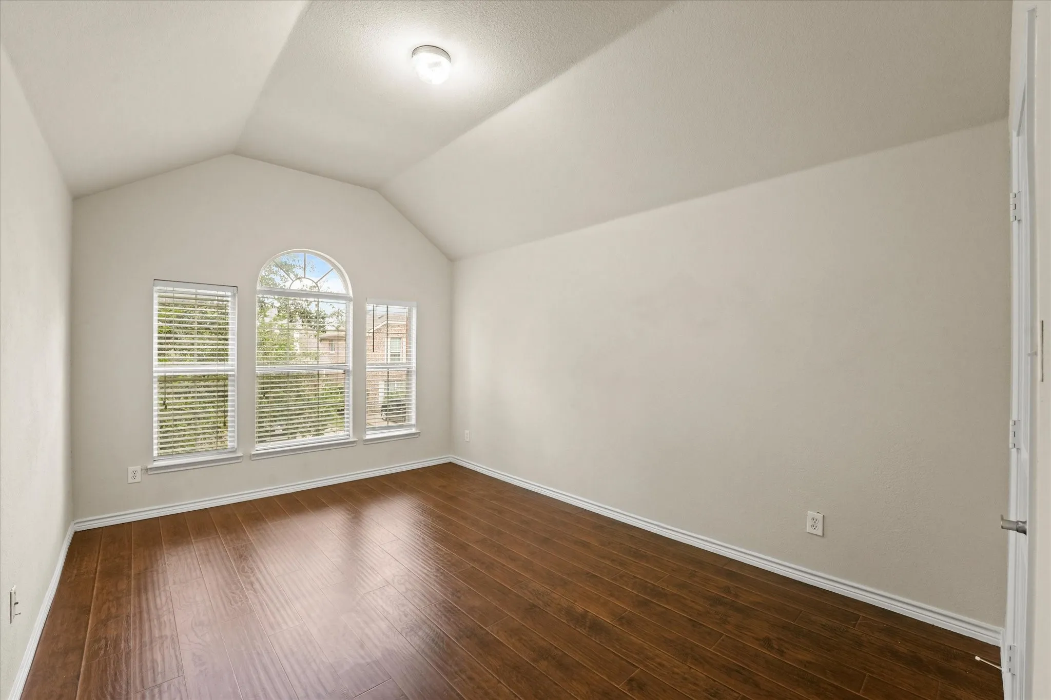 Unfurnished room featuring hardwood / wood-style flooring and lofted ceiling