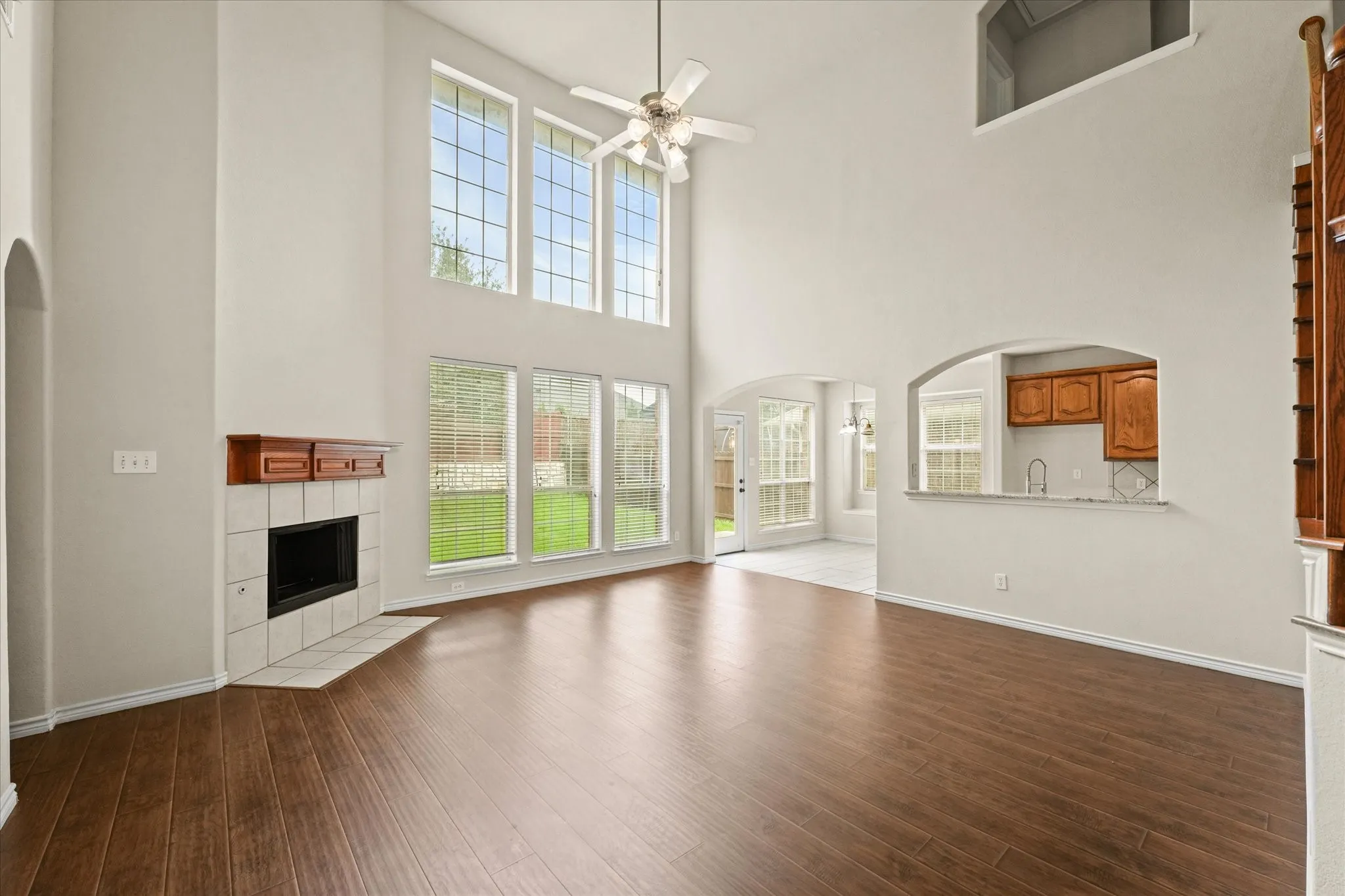 Unfurnished living room featuring a towering ceiling, hardwood / wood-style floors, ceiling fan, and a tile fireplace