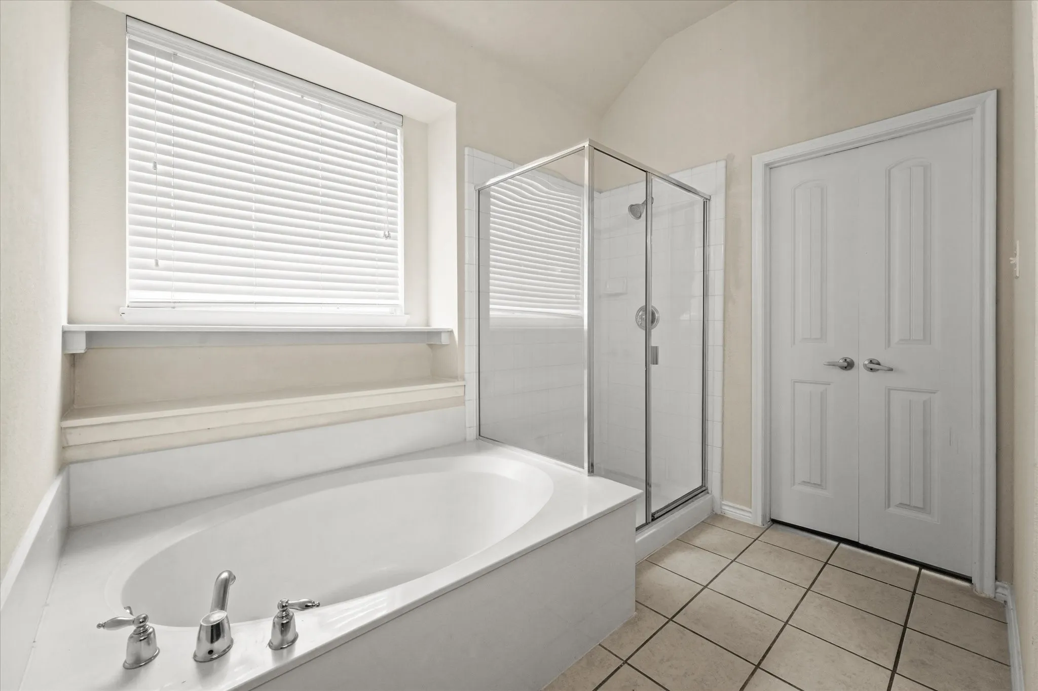 Bathroom with tile floors, lofted ceiling, and plus walk in shower