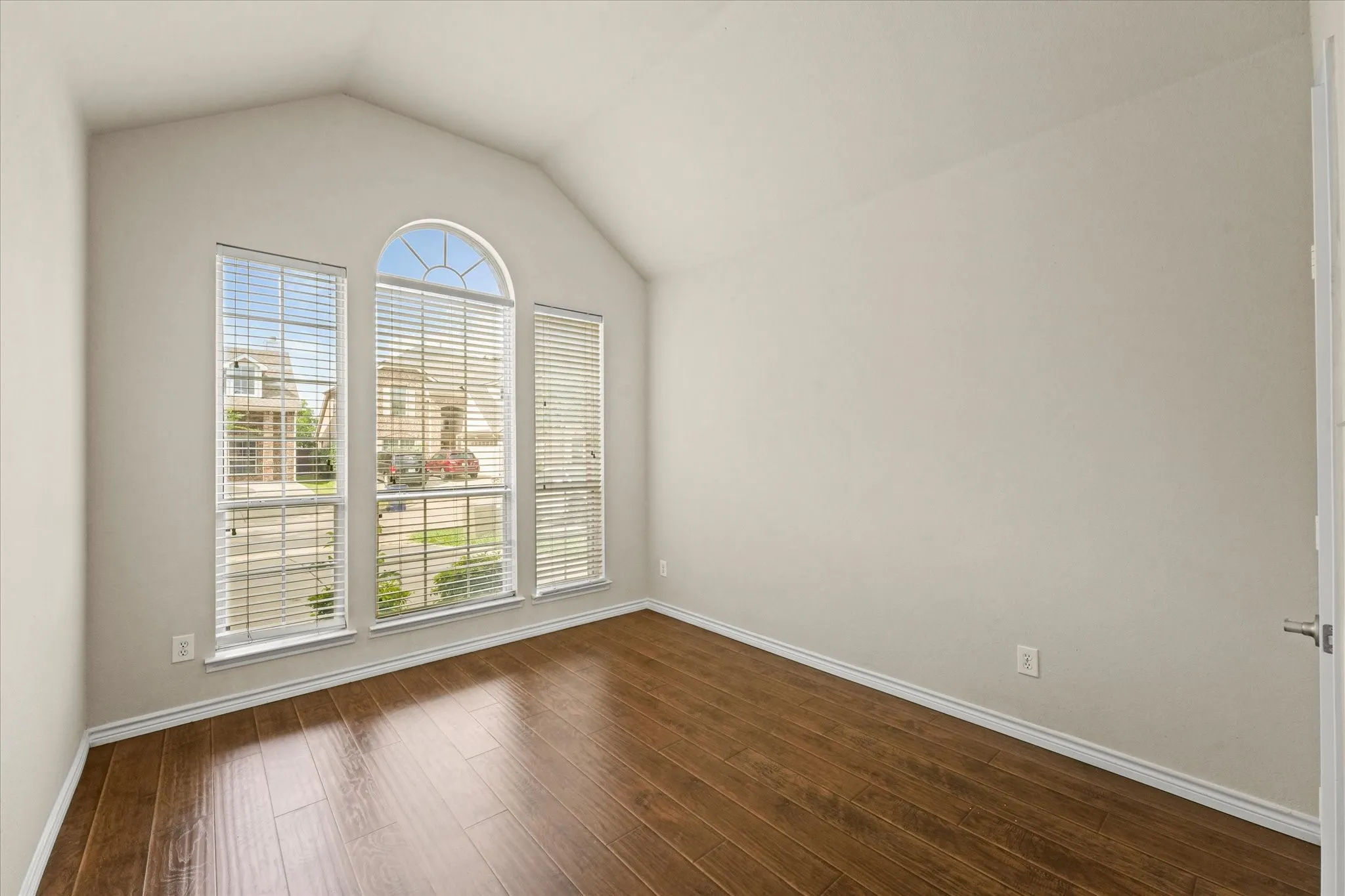Unfurnished room with dark hardwood / wood-style flooring, a wealth of natural light, and vaulted ceiling