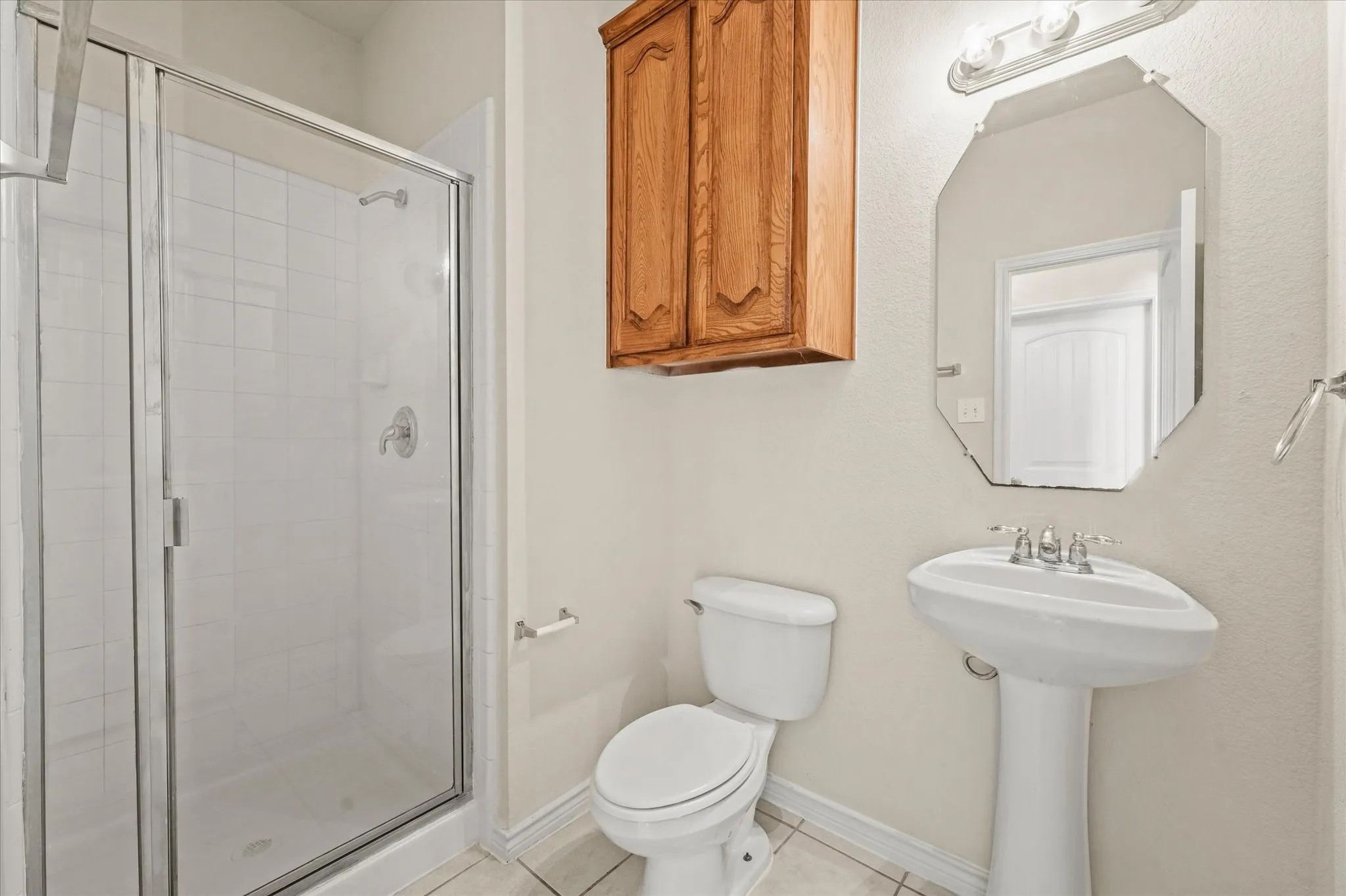 Bathroom with a shower with shower door, tile flooring, and toilet