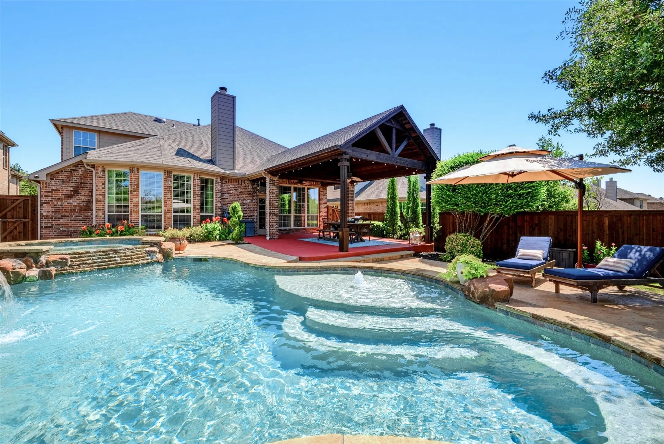 Step into your own private retreat where exceptional outdoor living takes center stage. This stunning backyard showcases a sparkling custom pool with elegant water features, tanning ledge  creating the perfect setting for relaxation and entertaining. The impressive covered cabana, highlighted by the vaulted ceilings, provides a true outdoor living area complete with ample space for dining, lounging, or gathering with family and friends.
Surrounded by lush landscaping, multiple conversation areas, this outdoor sanctuary offers the ultimate blend of comfort and sophistication. Whether enjoying a quiet morning by the pool, hosting summer celebrations, or unwinding beneath the covered patio, every detail has been thoughtfully designed to maximize enjoyment of the outdoor lifestyle.A rare combination of resort-inspired amenities and timeless architectural appeal, this property delivers the perfect combination of both.