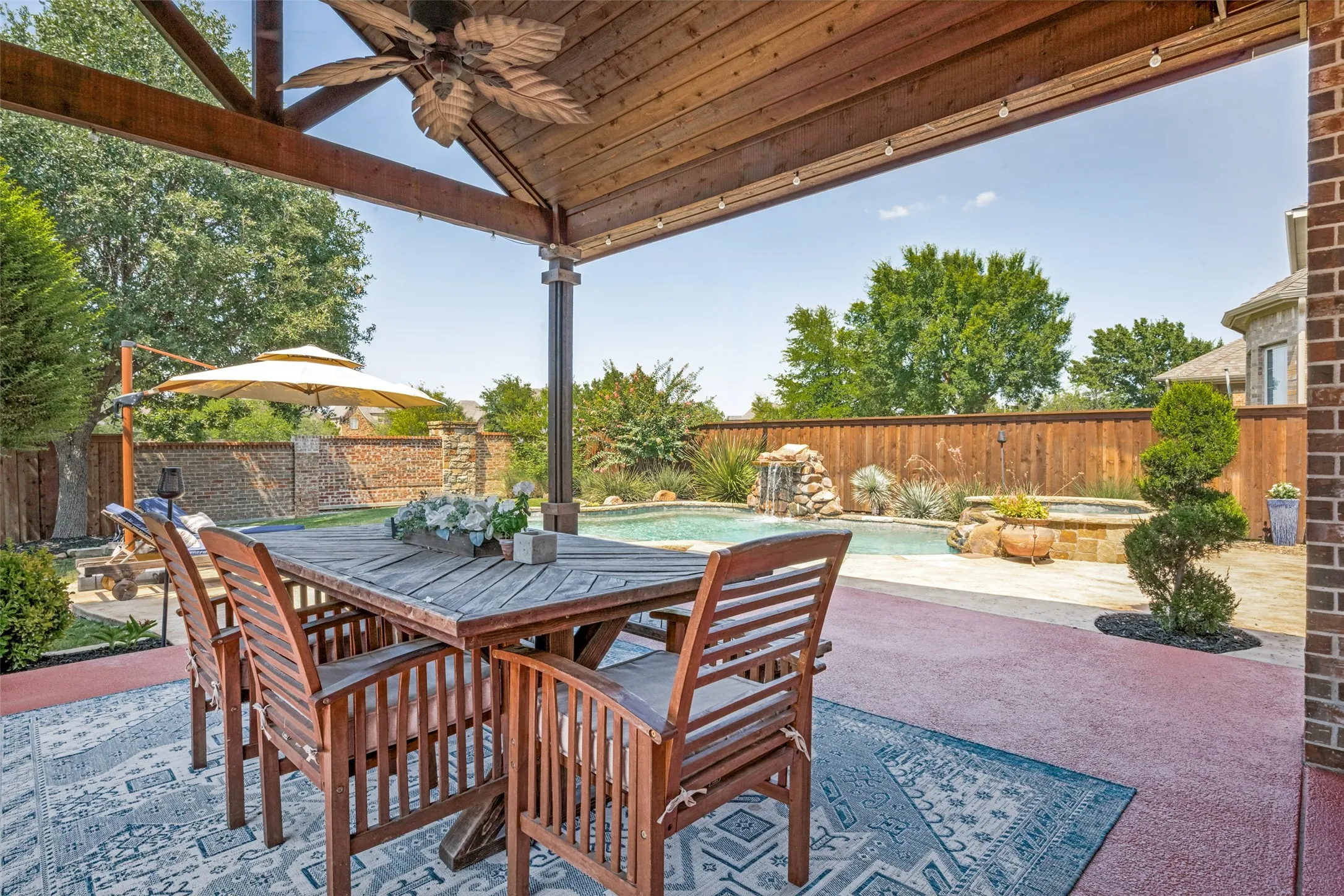 Enjoy your own private backyard retreat beneath a stunning covered cabana with a soaring wood tongue and groove ceiling. This inviting outdoor living space is ideal for al fresco dining, entertaining, or relaxing while overlooking the sparkling pool, spa, water-features and beautifully landscaped yard. With ample room for gathering and seamless access to the backyard oasis, it's the perfect extension of the home's living space.