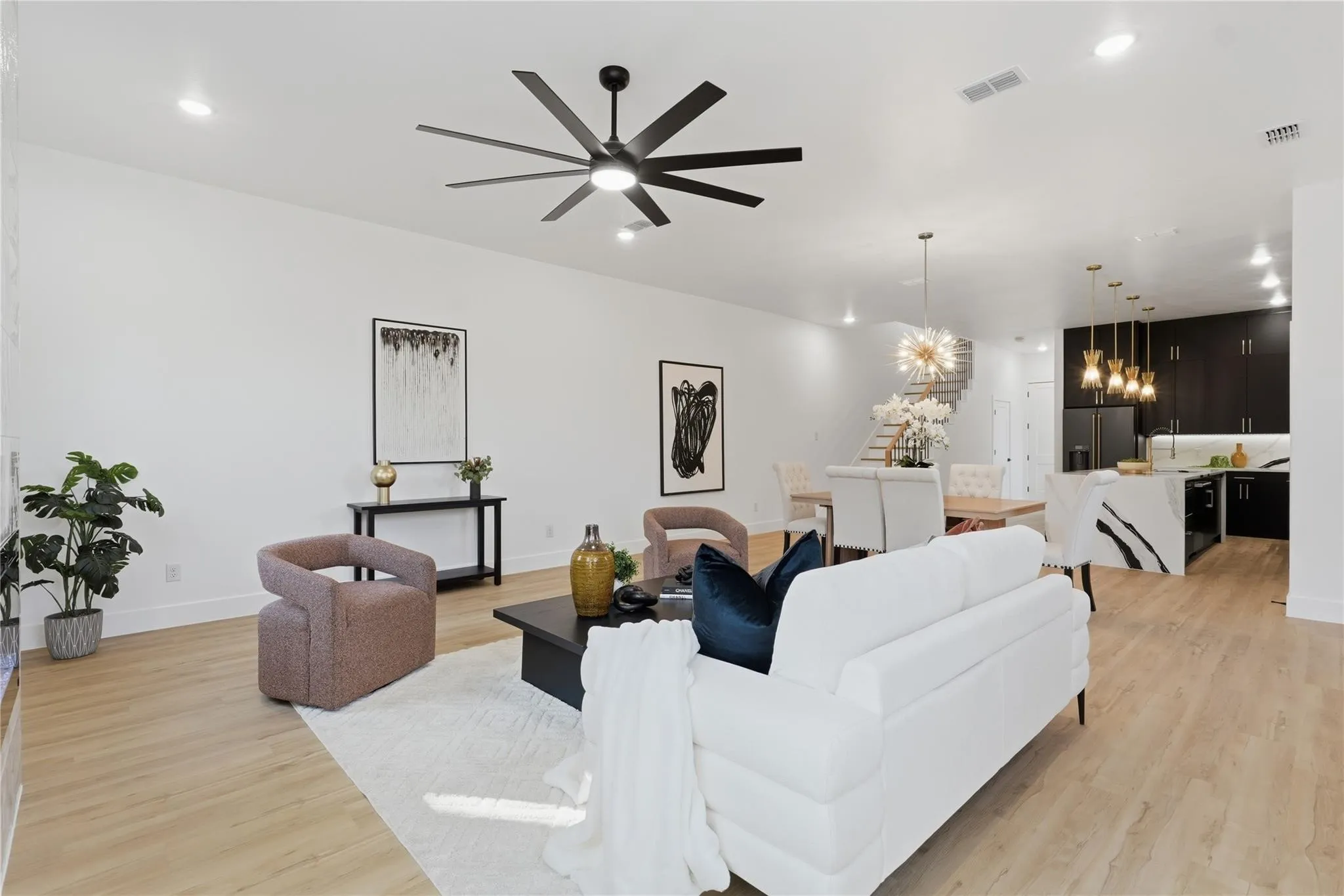 Spacious open-concept living area featuring light wood-finish flooring, recessed lighting, and a modern ceiling fan