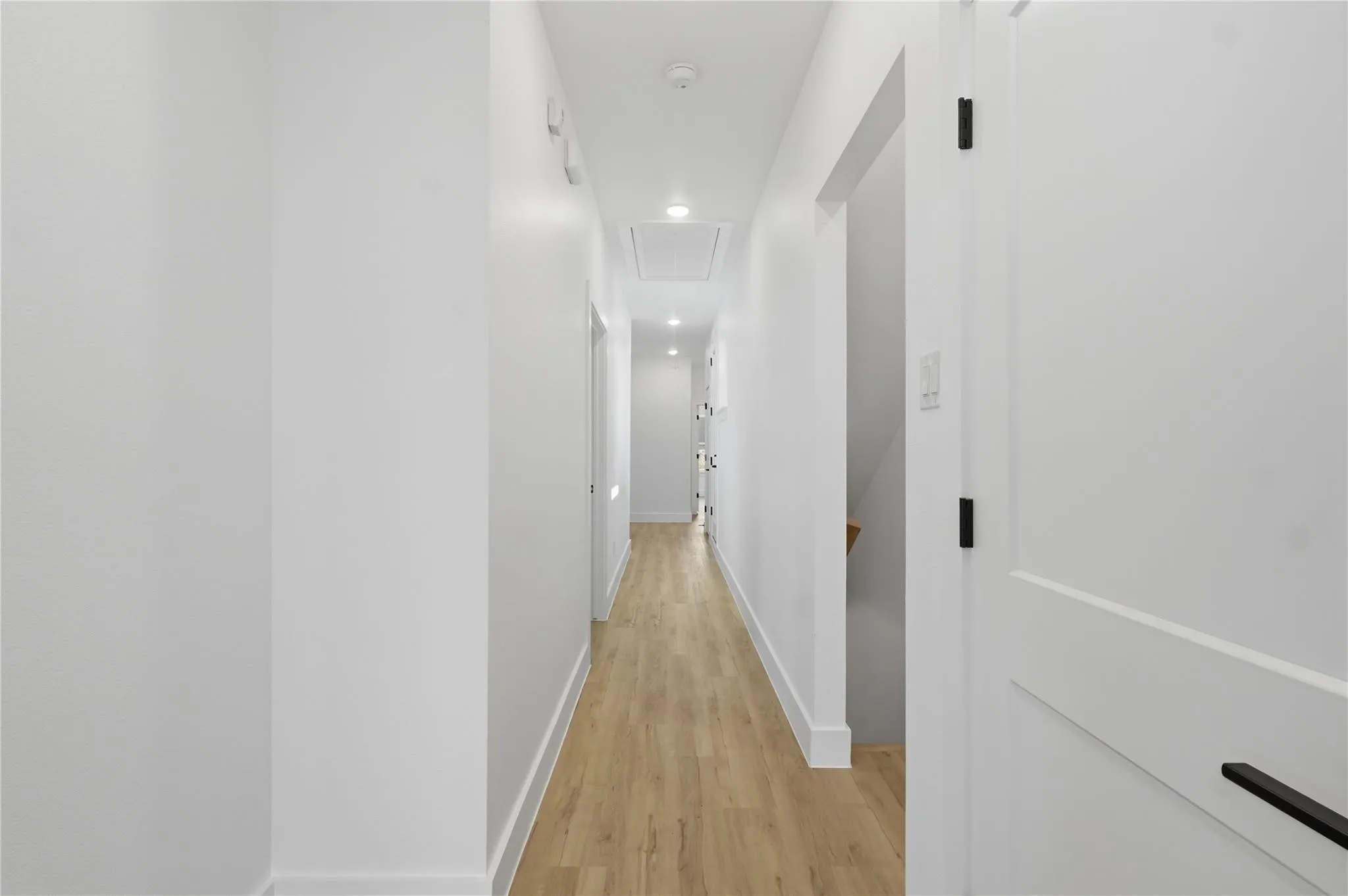 Hallway featuring wood-finish flooring, white walls, recessed lighting, and white trim