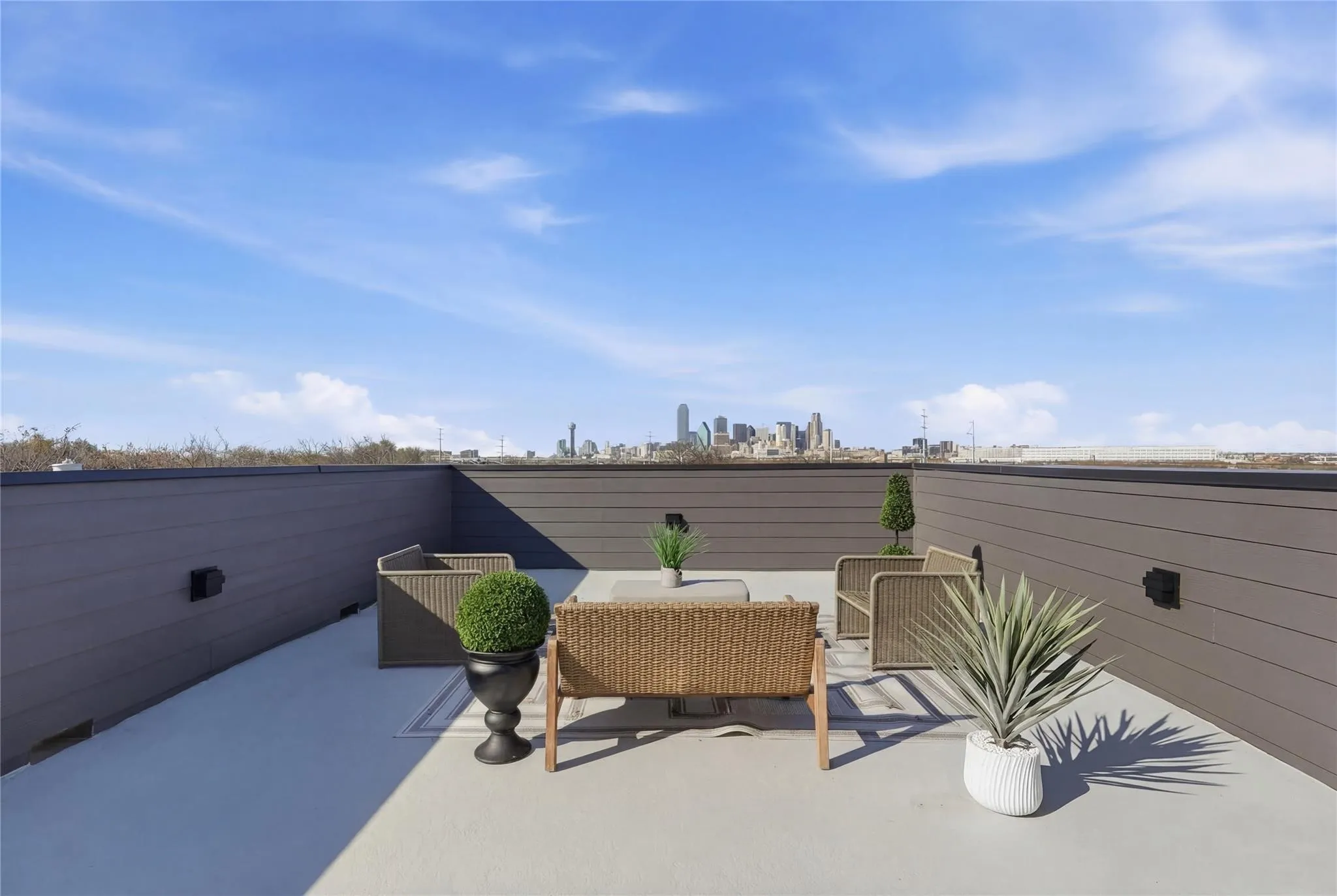 Rooftop deck featuring a city skyline backdrop, composite privacy walls, and a light-colored concrete surface