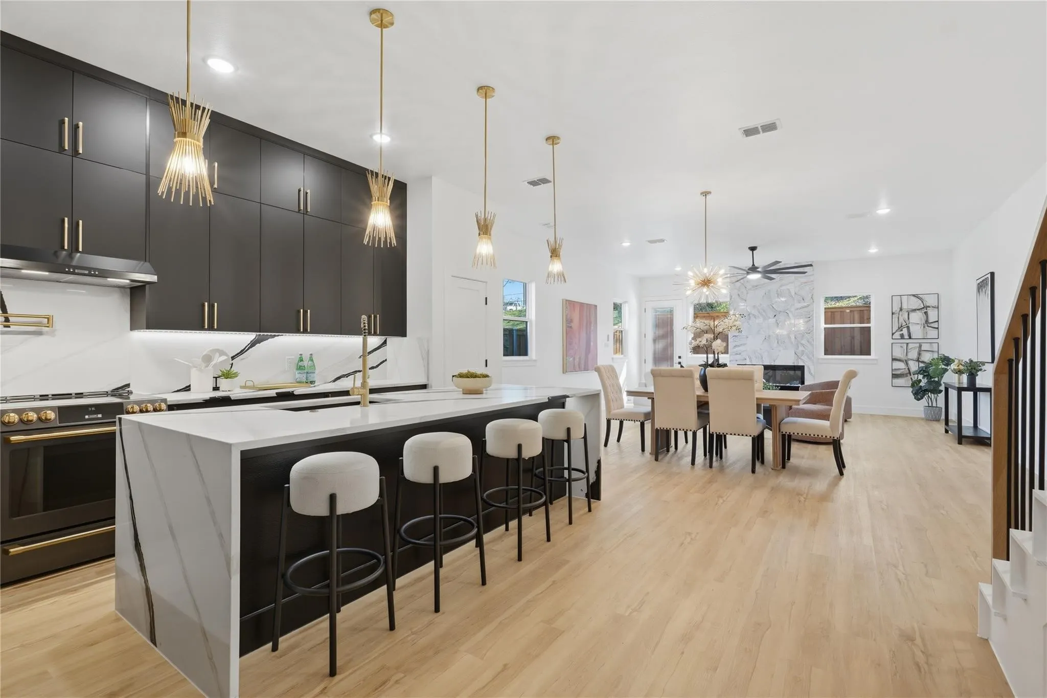 Modern kitchen featuring matte black cabinetry, a waterfall island with integrated seating, and gold-finish hardware and fixtures