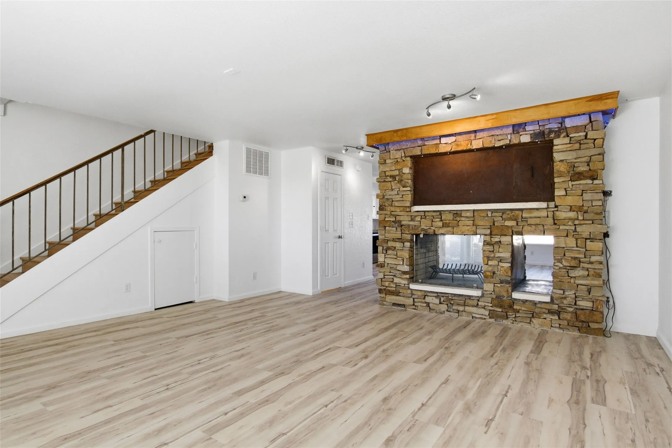 Modern stone fireplace with an integrated media niche, glass-enclosed firebox, and decorative LED lighting