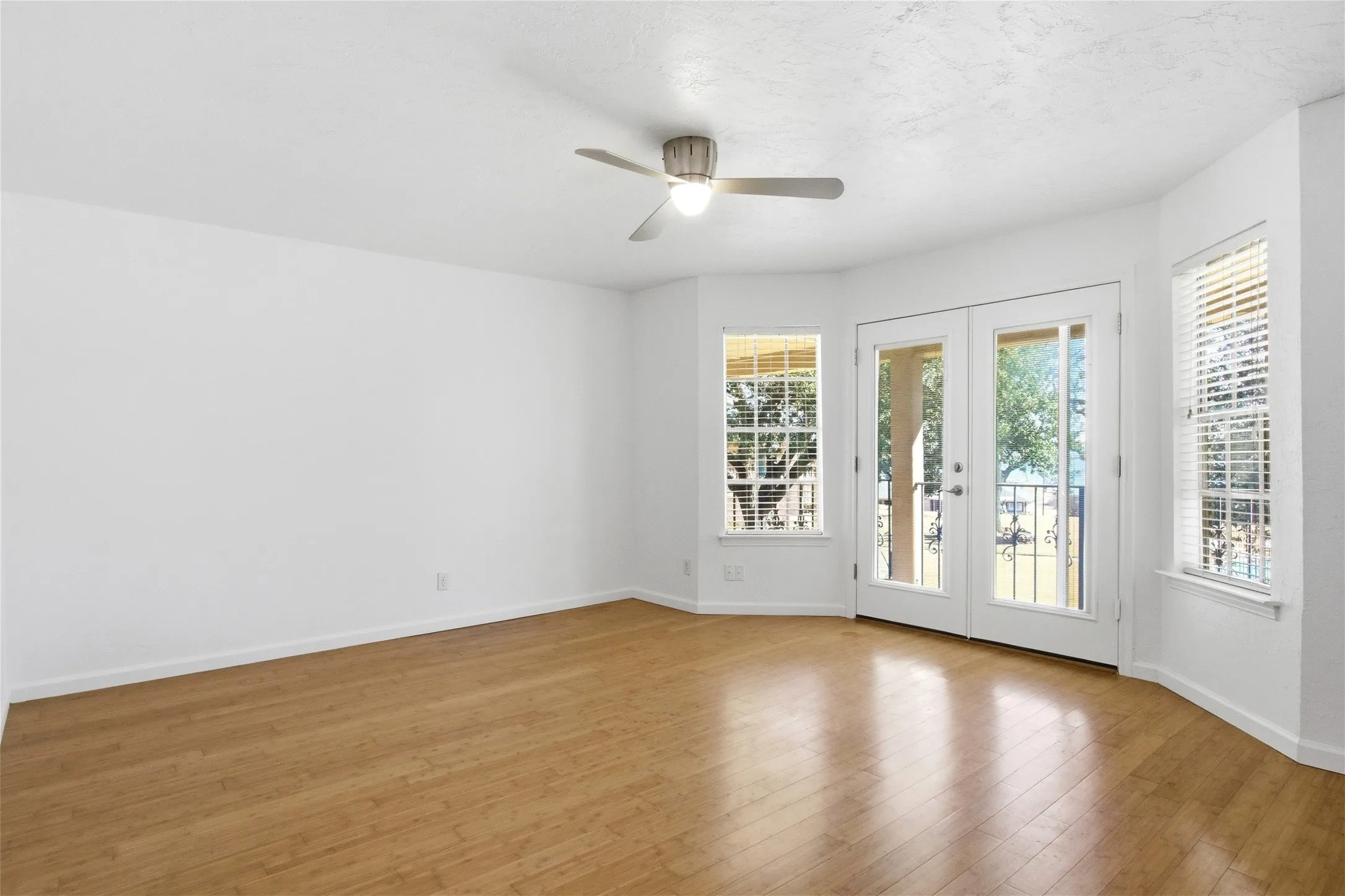 Open living space featuring wood-finish flooring and a contemporary ceiling fan with integrated lighting