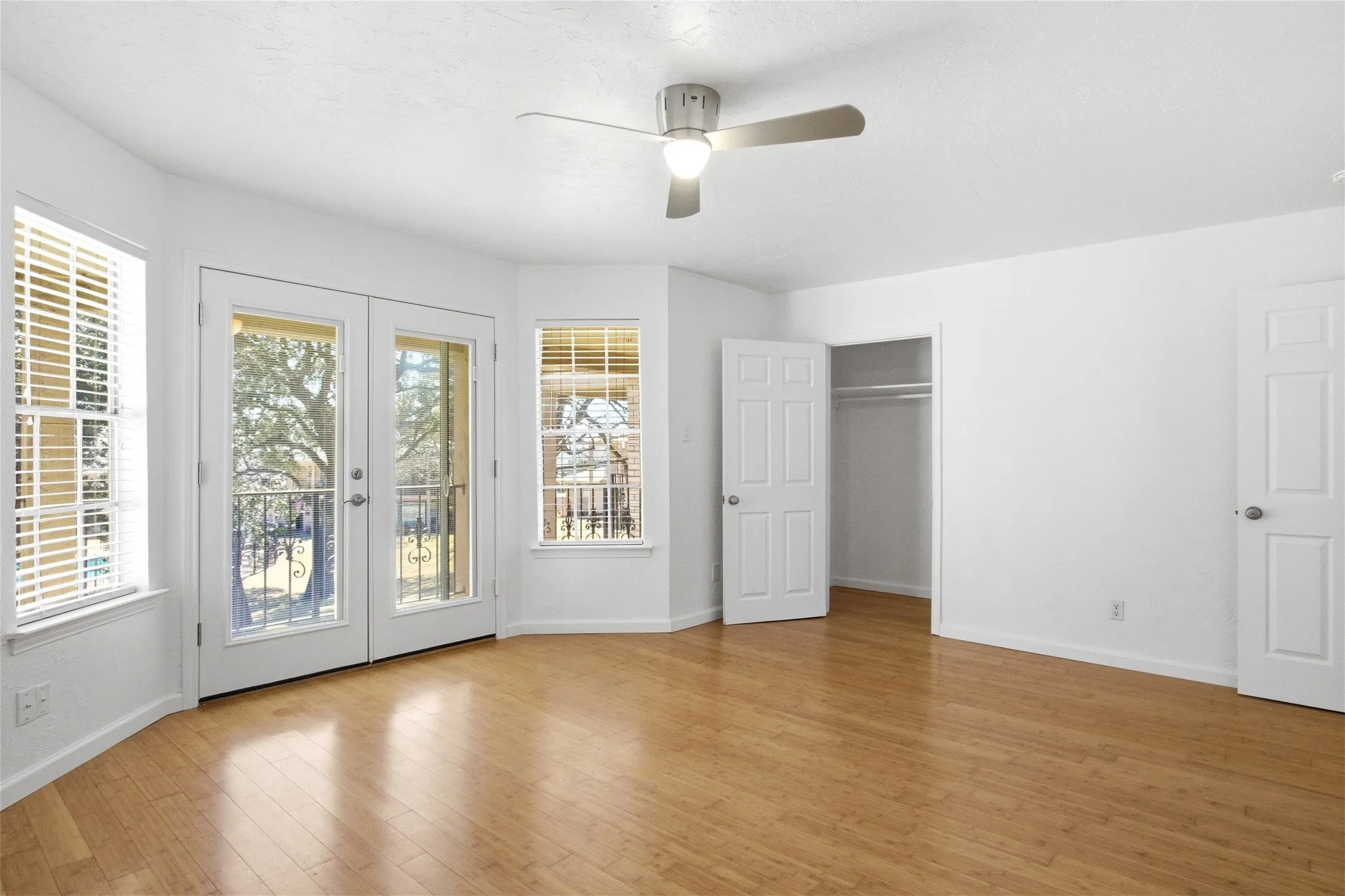 Bright interior featuring wood-finish flooring, a ceiling fan with integrated lighting, and white walls