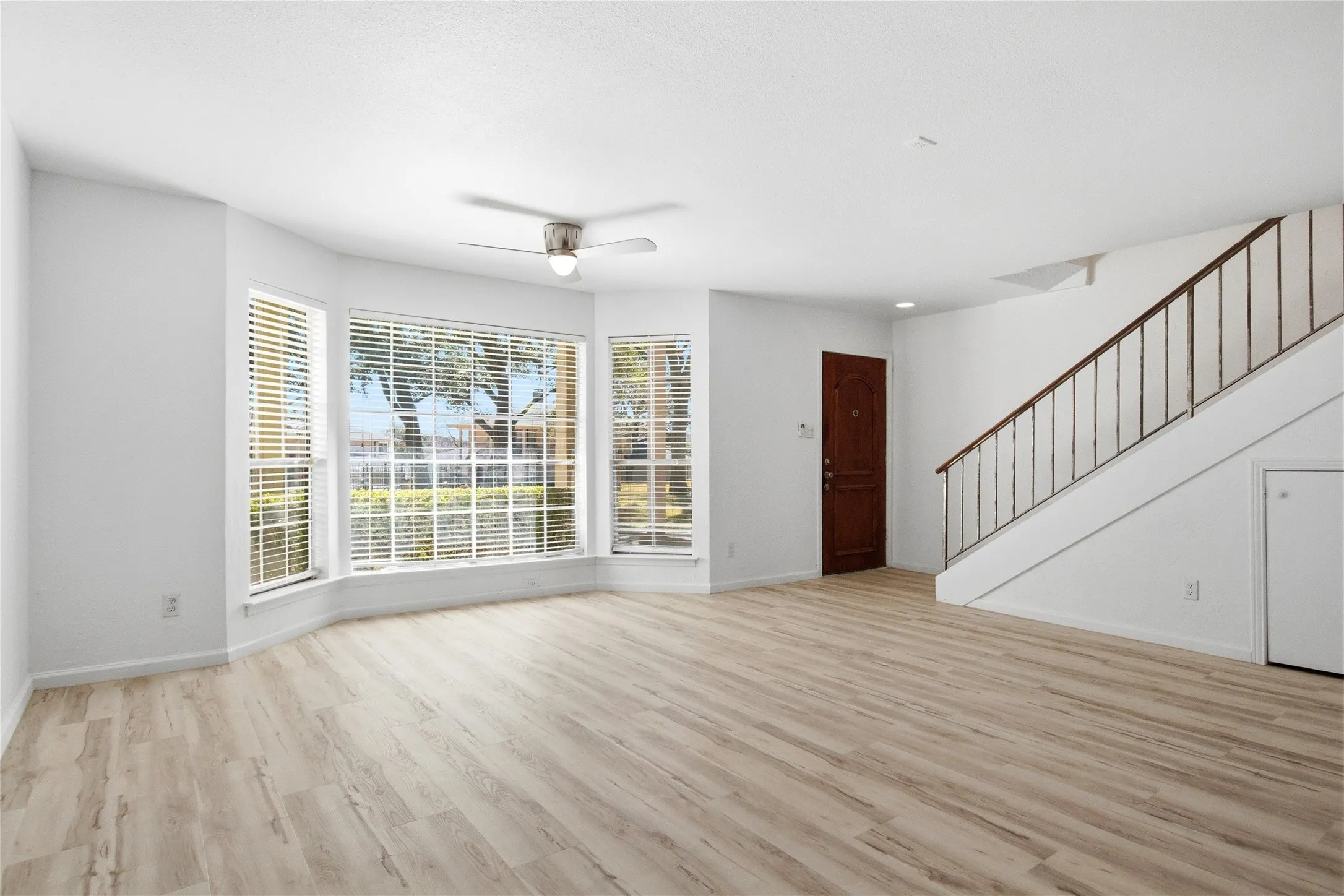 Open-concept living area featuring light wood-finish flooring and a multi-pane bay window