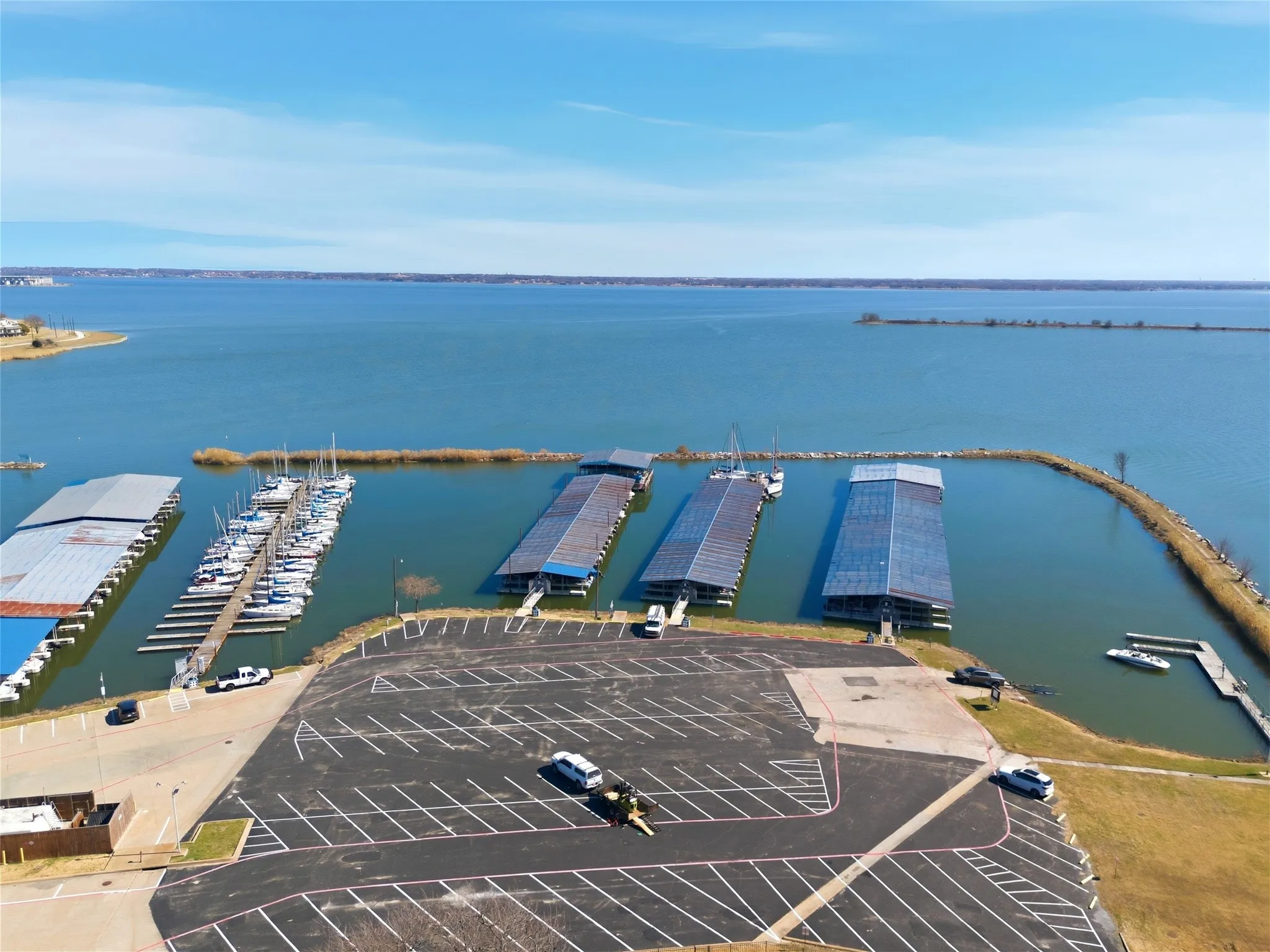 Expansive waterfront property featuring multiple boat slips, covered boat storage, and a substantial parking area