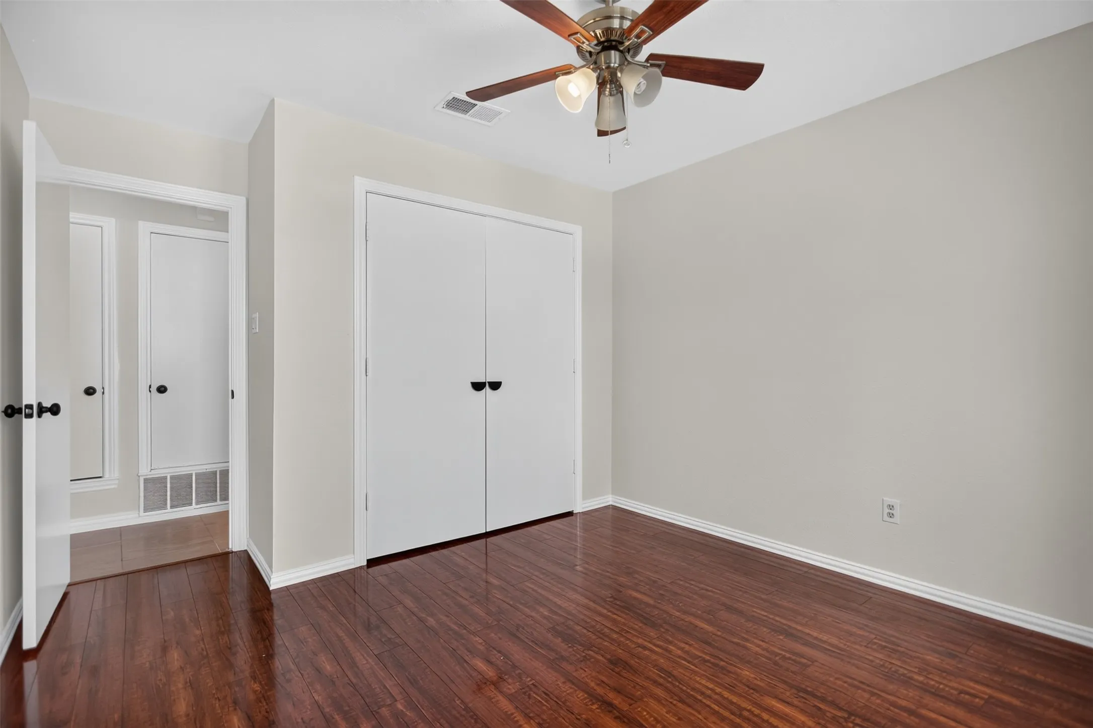 Room featuring wood-finish flooring, a ceiling fan with integrated lighting, and neutral wall paint