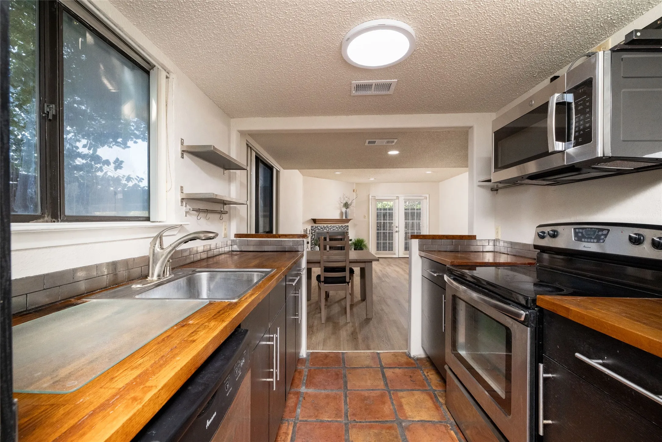 Kitchen featuring wood countertops, stainless steel appliances, and a tile floor