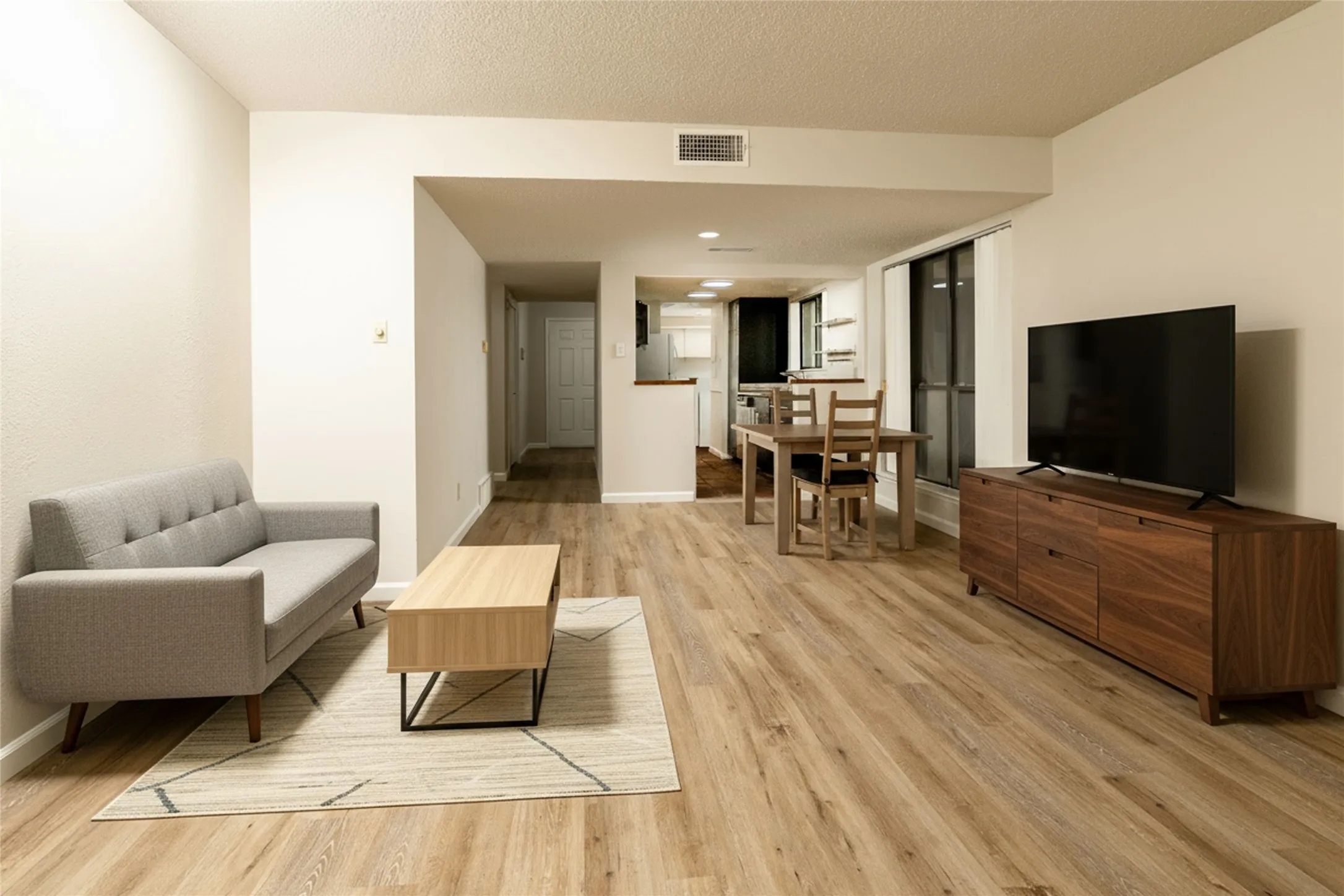 Spacious living area featuring wood-finish flooring, neutral wall tones, and recessed ceiling lighting