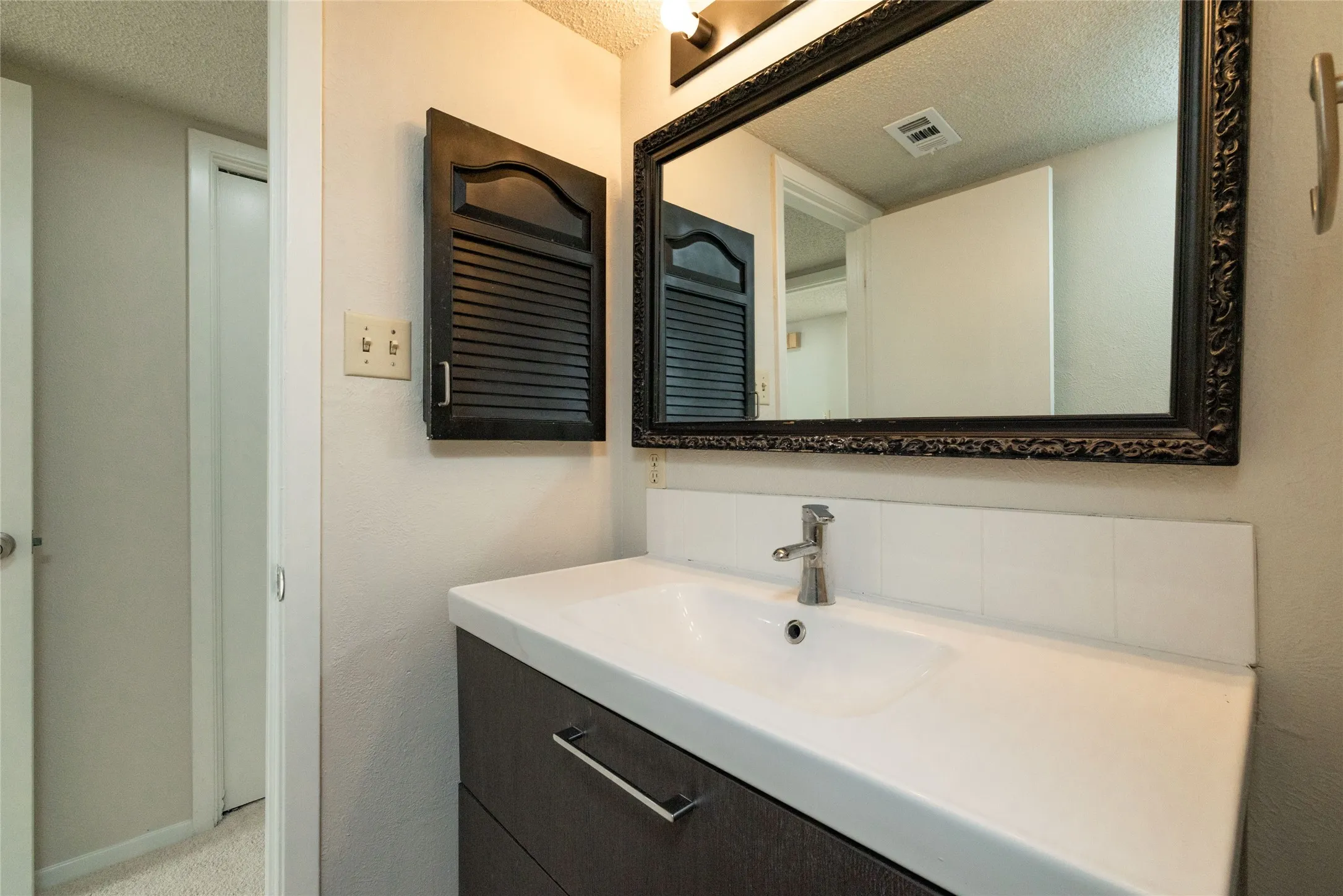 Modern vanity with integrated sink, brushed nickel faucet, and dark wood-finish cabinetry