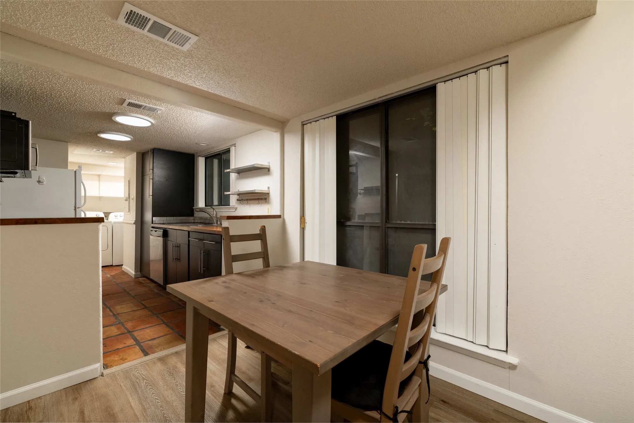 Dining area featuring wood-finish flooring and a large window with vertical blinds