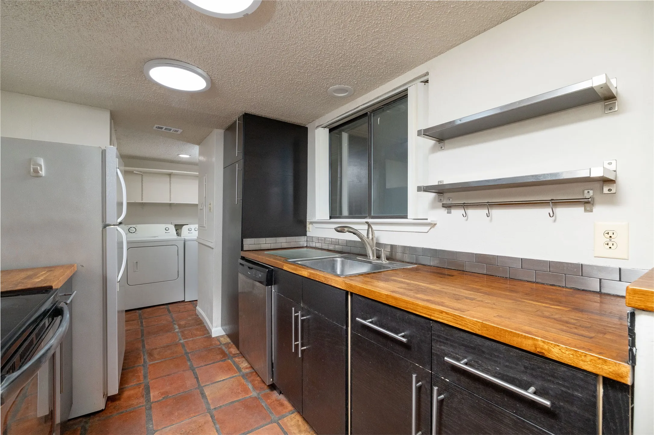 Kitchen with wood-finish countertops, dark cabinetry, and stainless steel appliances