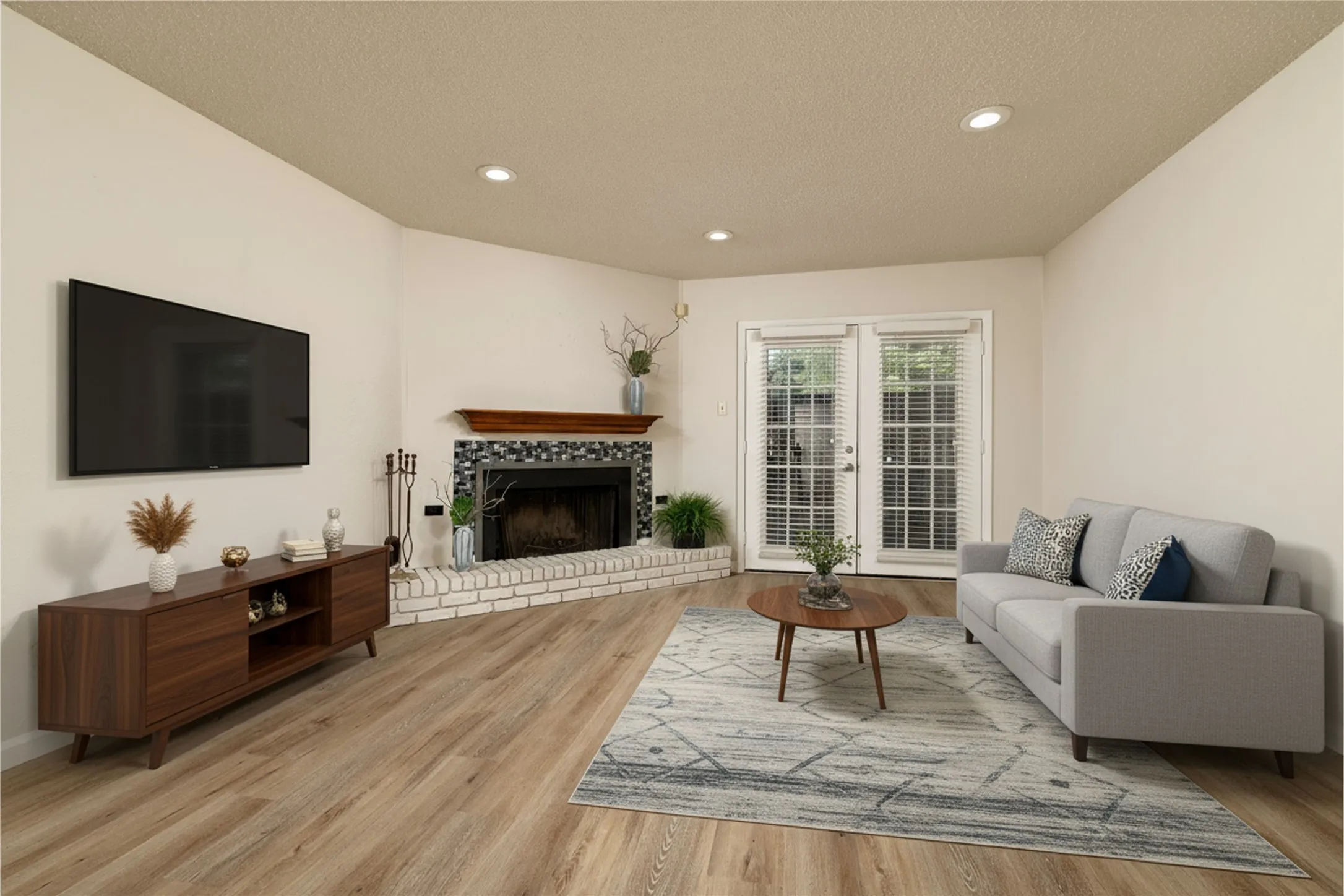 Living area featuring wood-finish flooring, a white brick fireplace with a wood mantel and mosaic tile surround, and recessed lighting