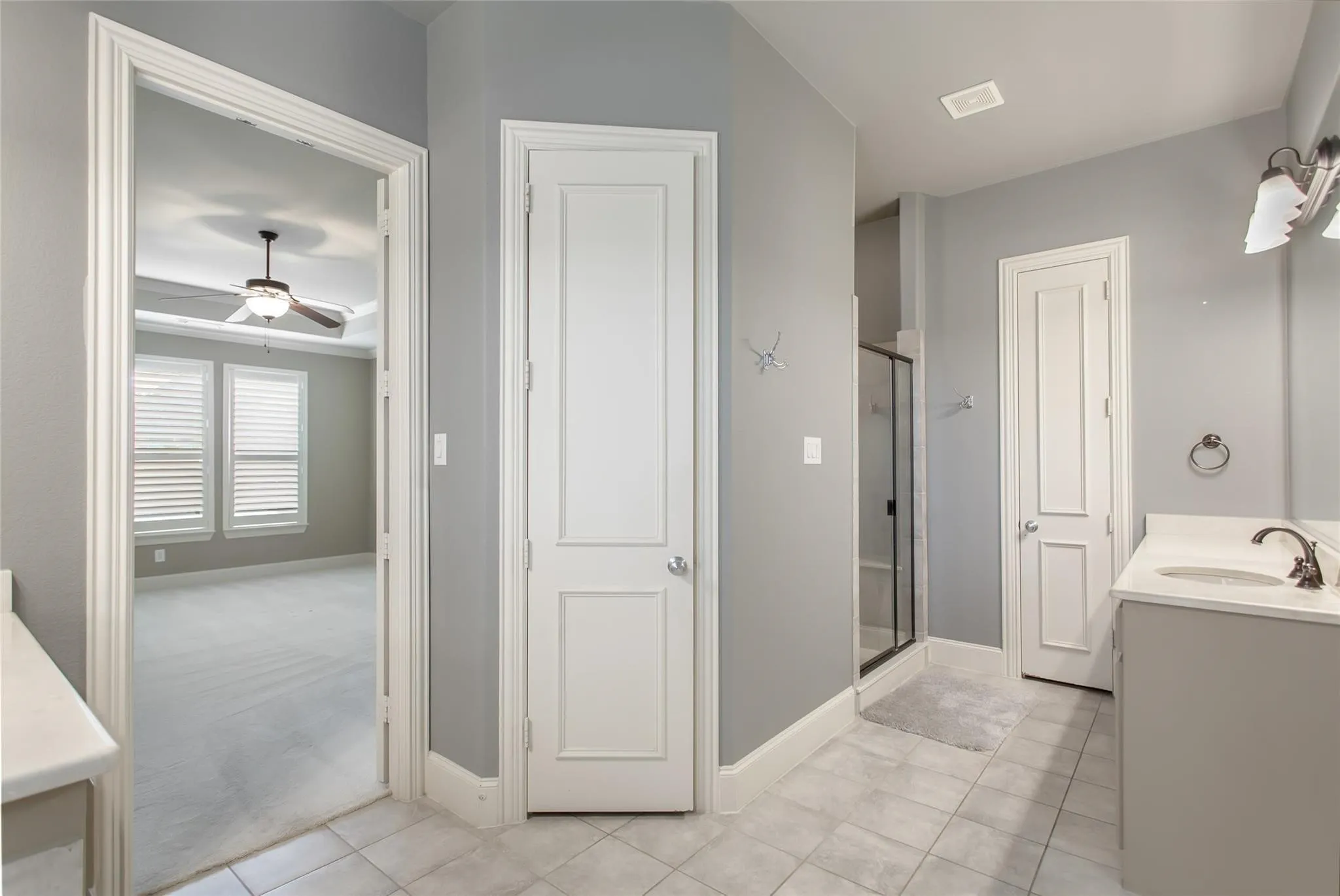 Bathroom featuring tile flooring, a single vanity with an undermount sink, and a glass-enclosed shower