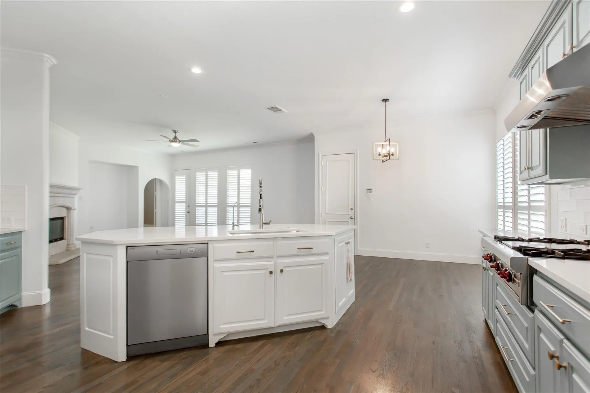 Spacious kitchen featuring an expansive central island with integrated sink and dishwasher, white cabinetry, light countertops, and dark wood-finish flooring