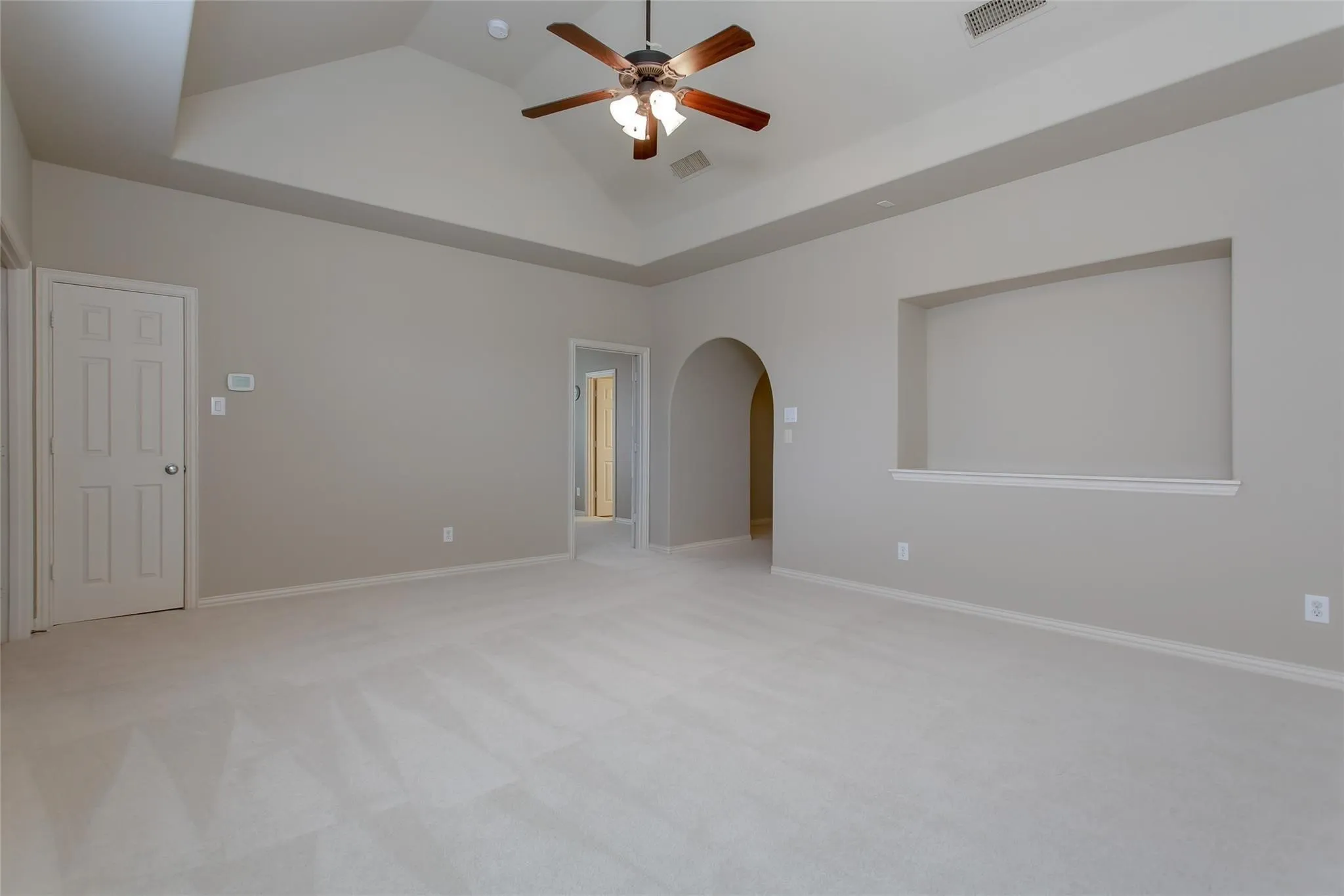 Spacious room featuring a vaulted ceiling with a ceiling fan, plush carpeting, and neutral wall tones