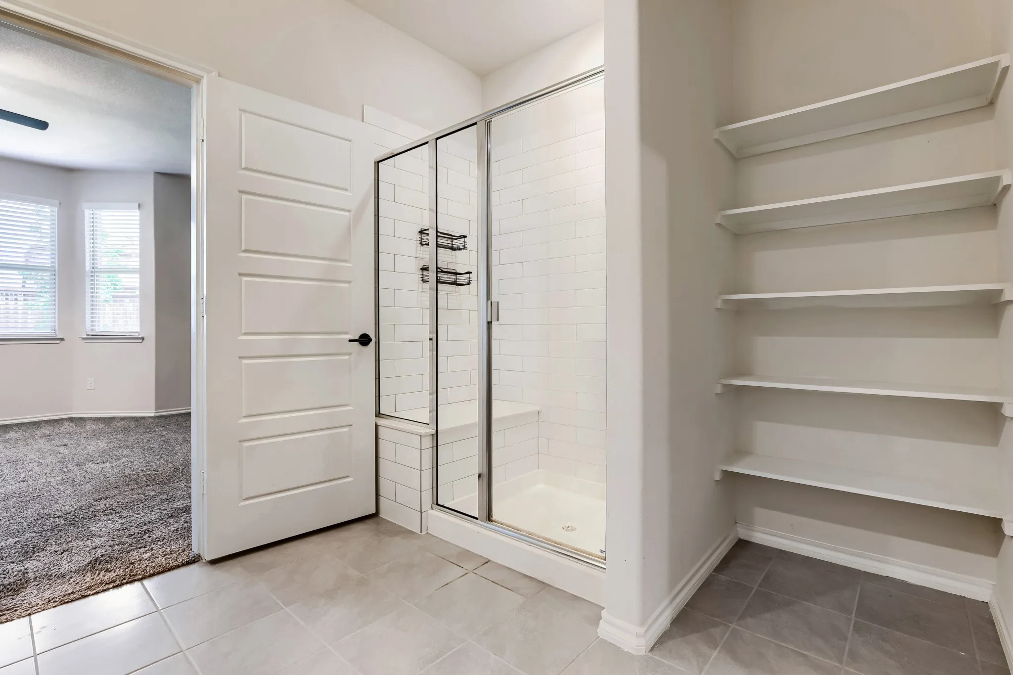 Glass-enclosed shower with subway tile surround and integrated bench