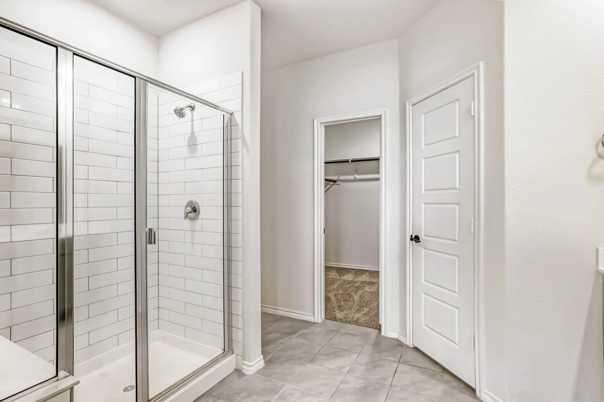 Glass-enclosed shower with subway tile surround, chrome shower fixtures, and a shower bench