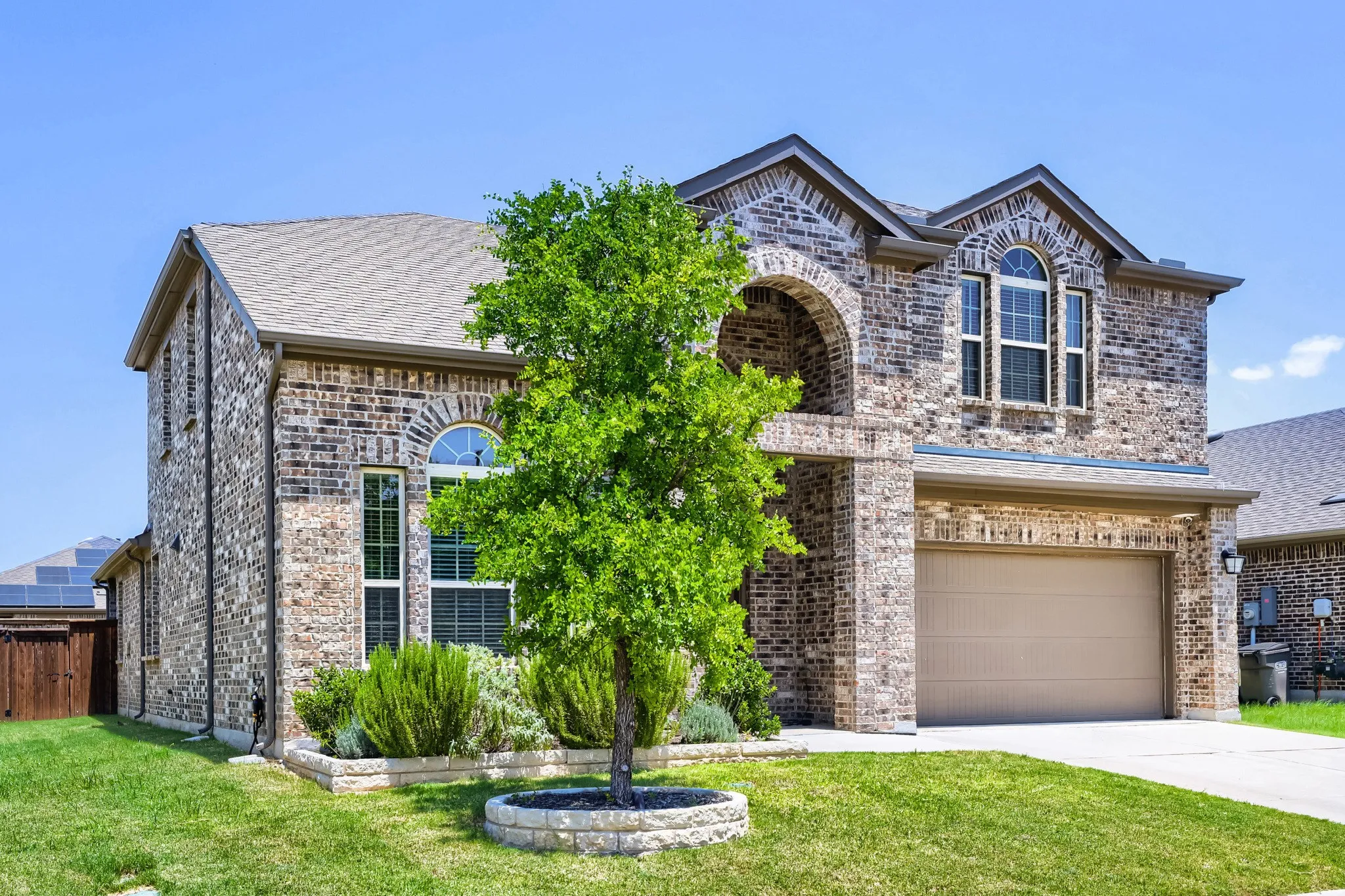 Brick exterior featuring arched architectural details, a two-car garage, and a gabled roof