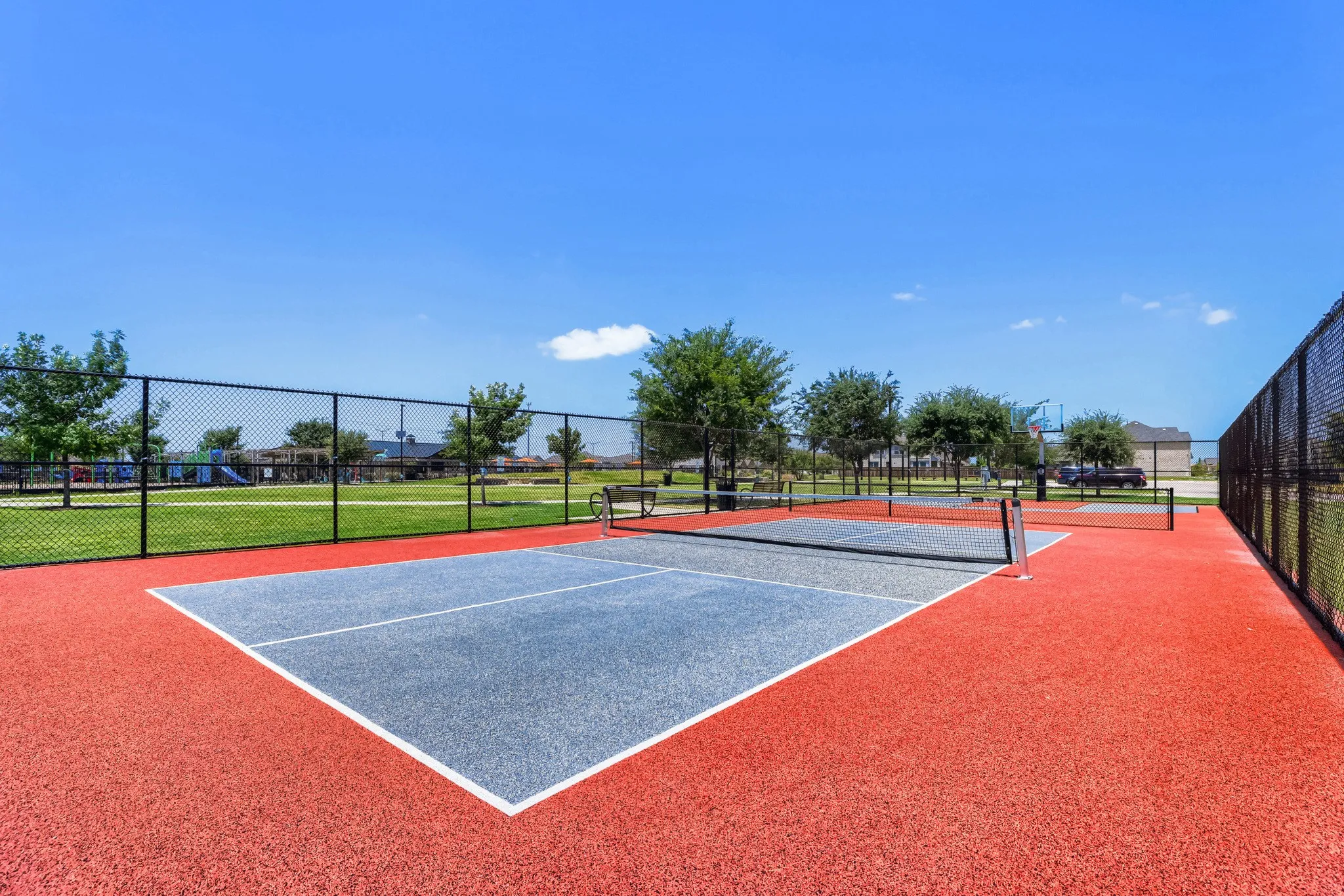 Red and gray multi-sport court with fencing and a net