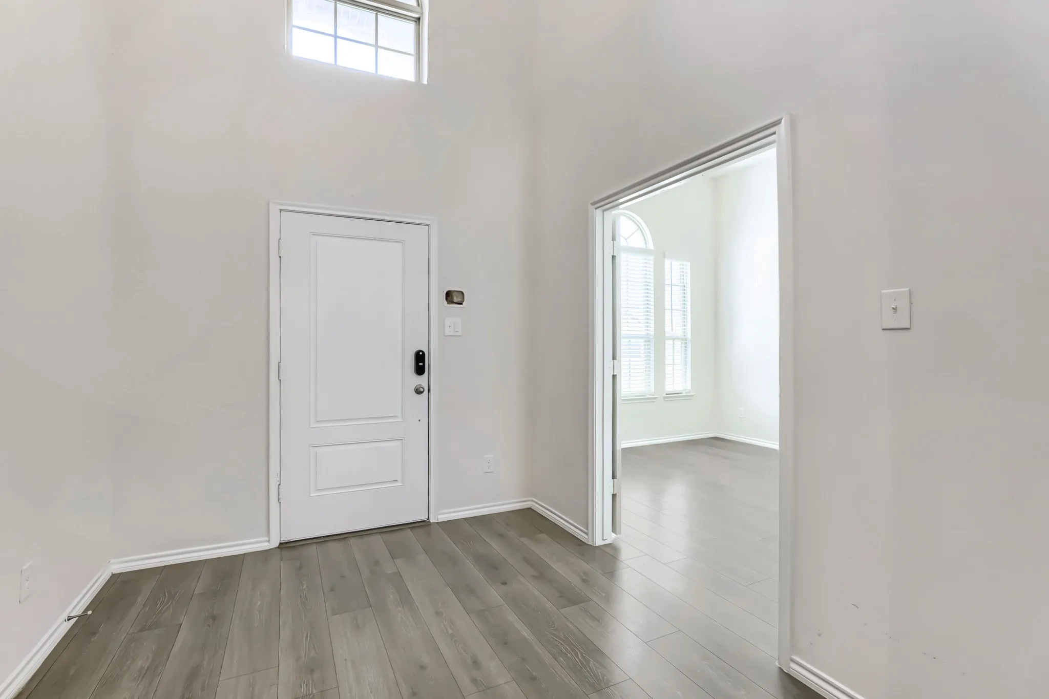 High ceilings with a transom window, wood-finish flooring, and a white paneled door