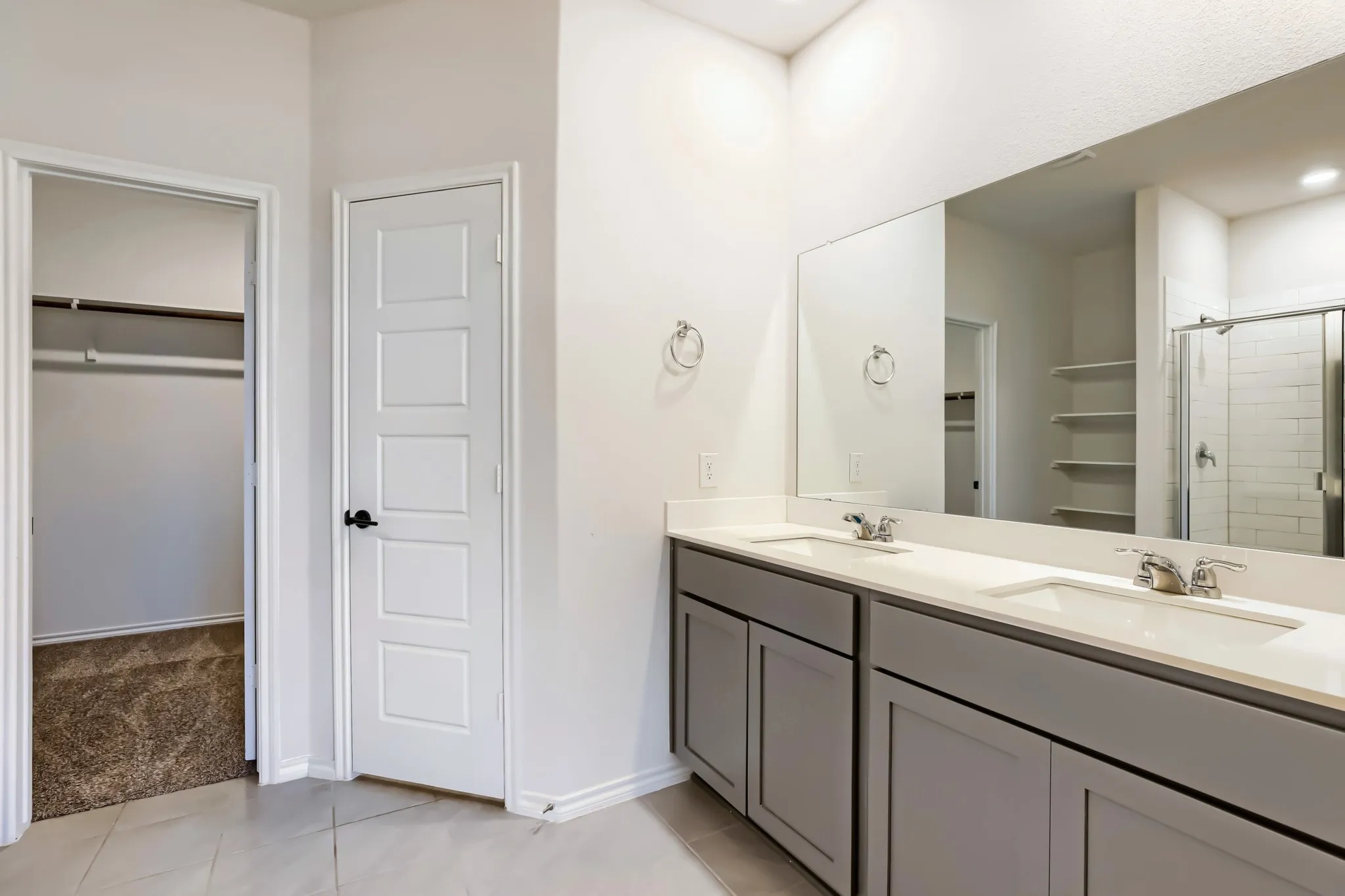 Dual vanity with undermount sinks, stone countertops, and gray cabinetry