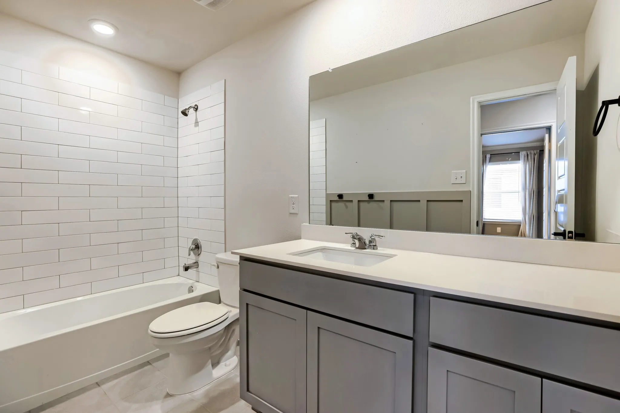 Bathroom featuring a single vanity with gray cabinetry, a white countertop, a built-in rectangular sink, and a large wall-mounted mirror