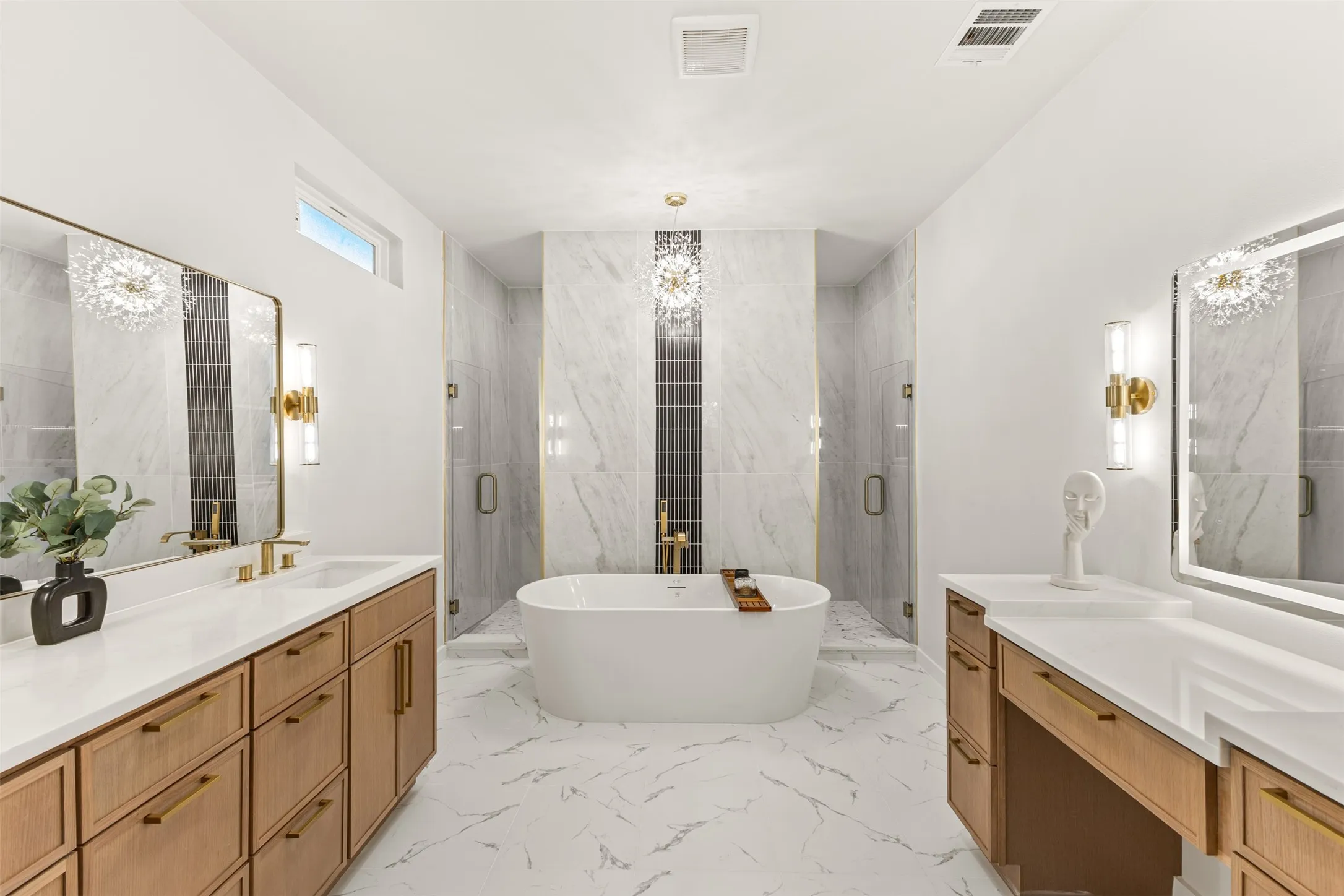 Contemporary bathroom featuring a freestanding soaking tub, dual glass-enclosed shower stalls, custom wood-finish vanities with white countertops, and white marble-look flooring