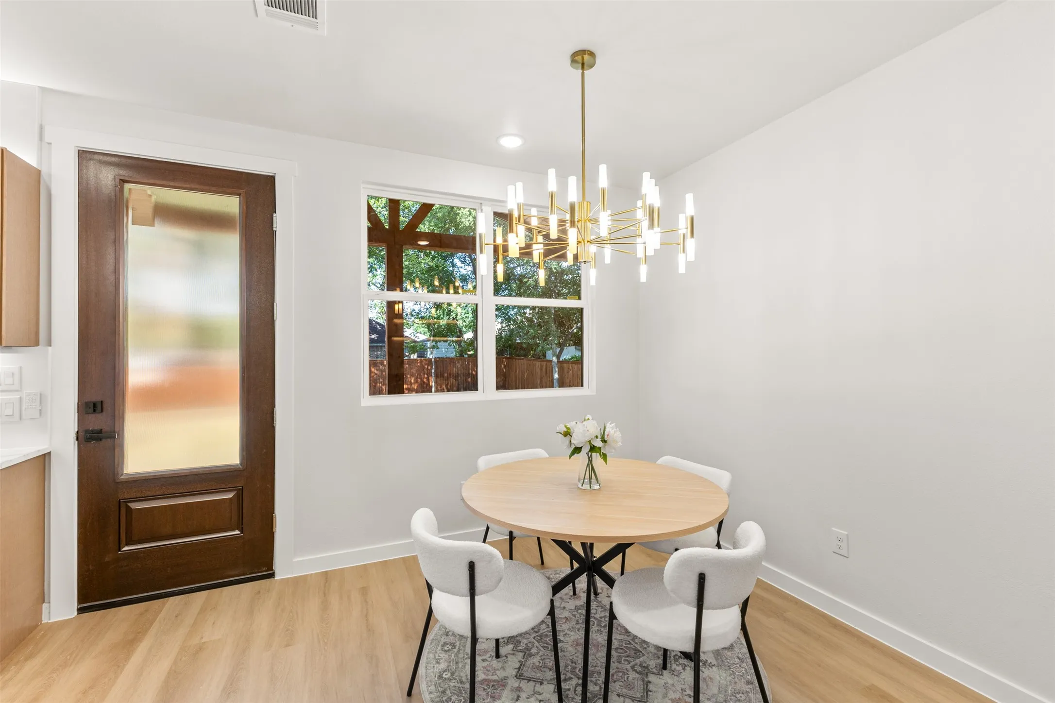 Dining area featuring a contemporary brass chandelier, wood-finish flooring, and white walls