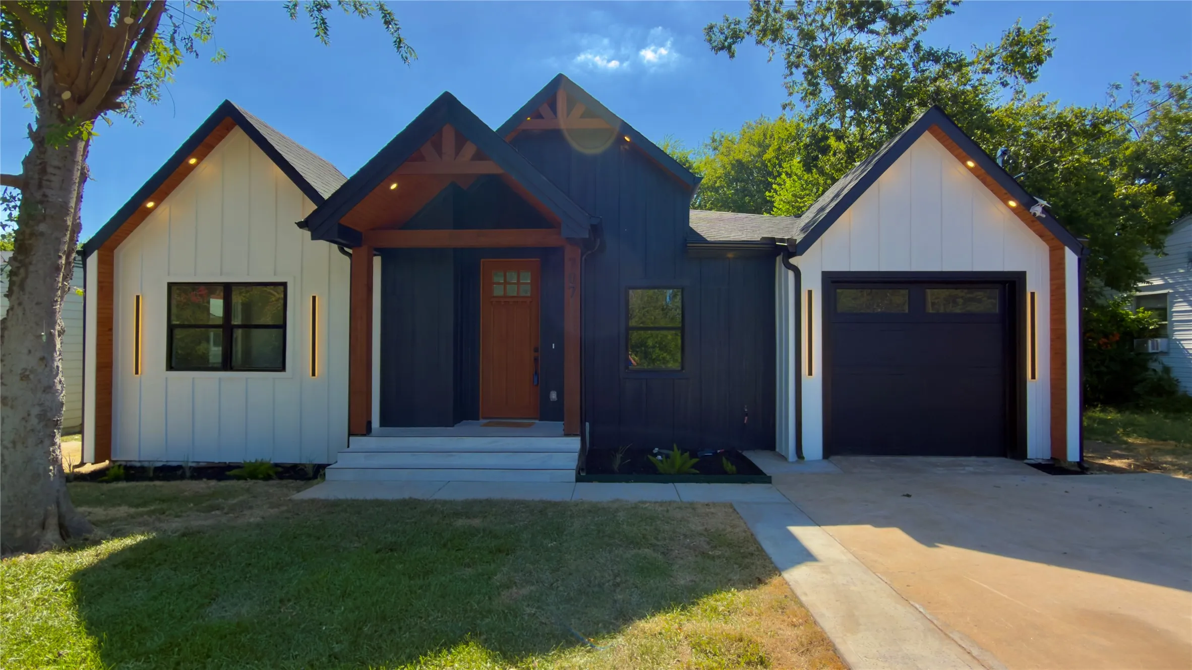 Modern farmhouse exterior featuring dark vertical siding, white board and batten accents, and a contrasting natural wood entry door
