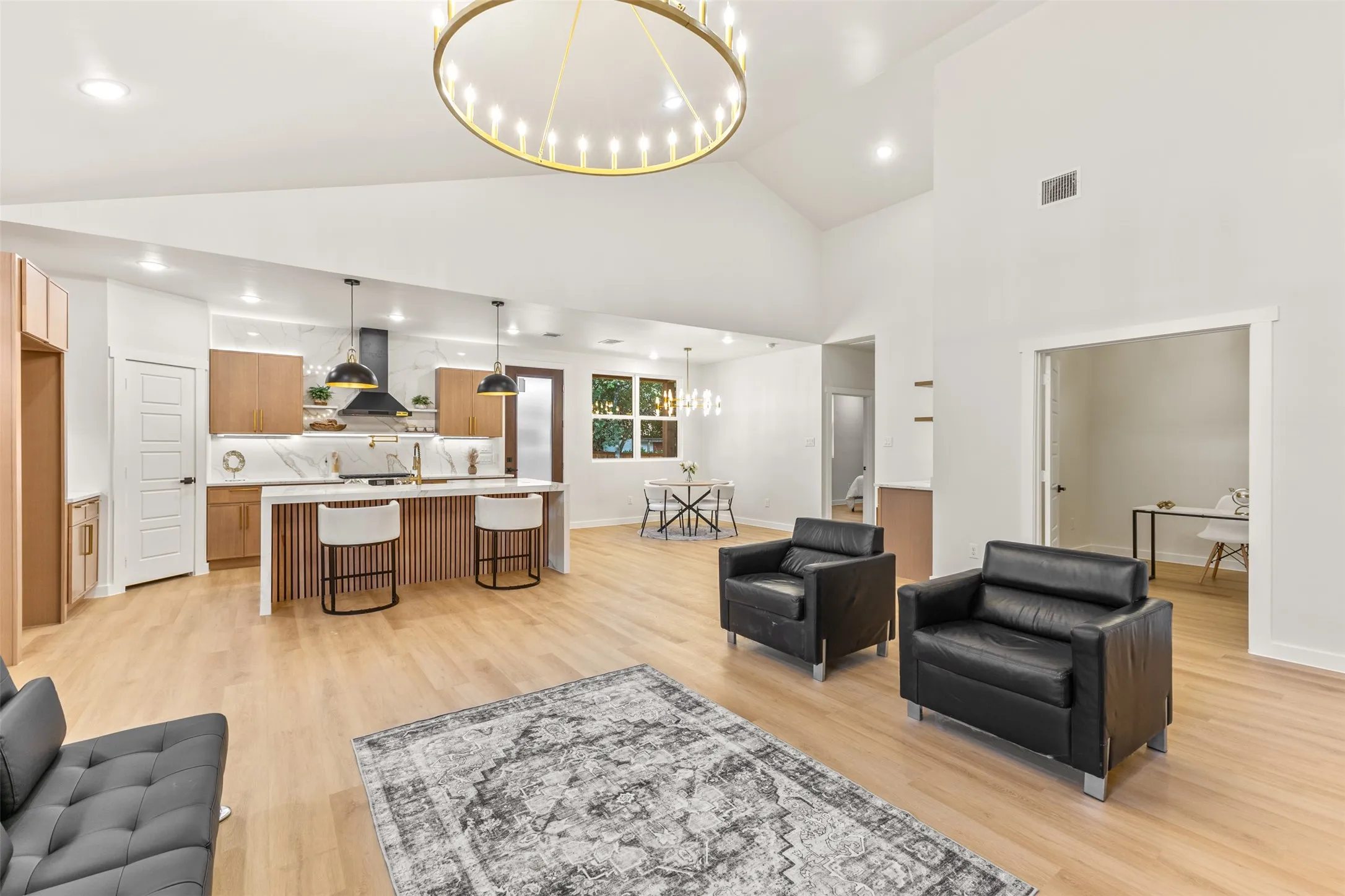 Open-concept living area featuring high vaulted ceilings, light wood-finish flooring, and recessed lighting