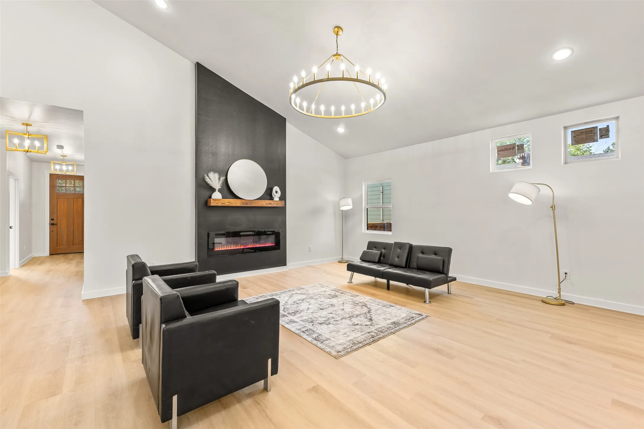 Spacious living area featuring a vaulted ceiling and light wood-finish flooring