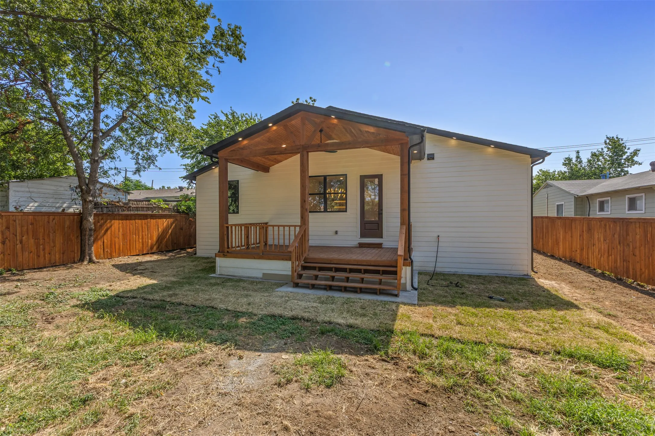 Rear exterior featuring a covered wood deck, wood privacy fencing, and a light-colored siding facade