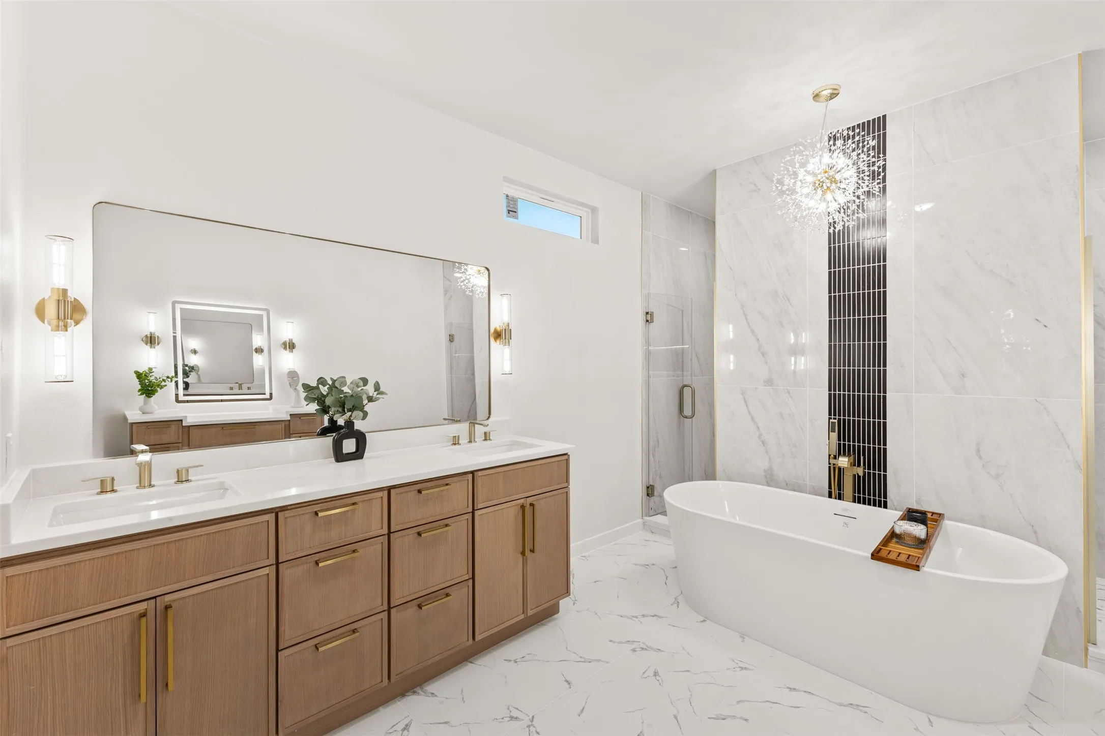Spacious bathroom featuring a dual vanity with wood-finish cabinetry, a large walk-in shower with glass enclosure, a freestanding soaking tub, and marble-look tile flooring and walls