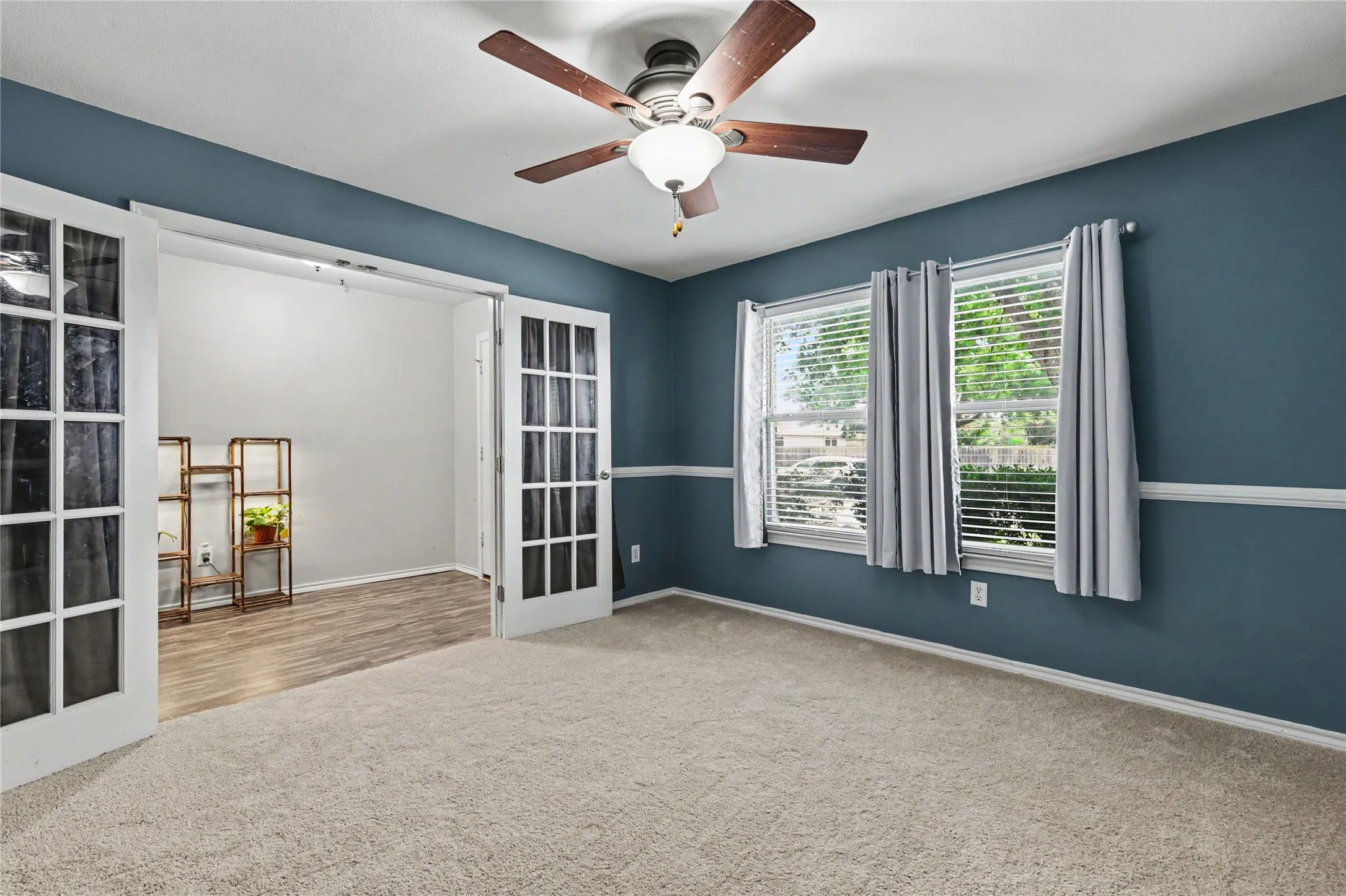 Room featuring a ceiling fan, dual windows with blinds, and white trim accents