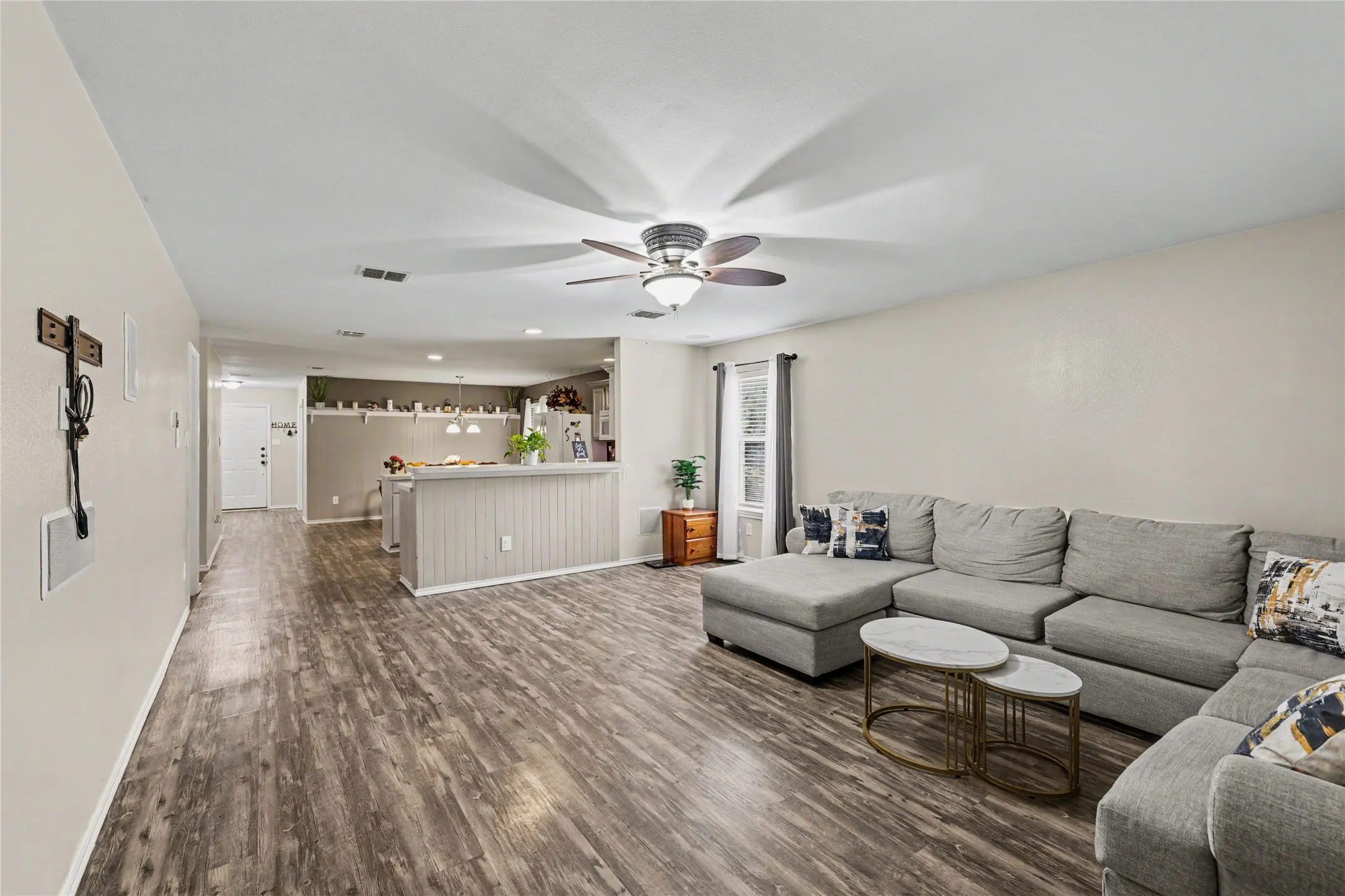 Spacious living area featuring wood-finish flooring, a ceiling fan, and light neutral wall colors