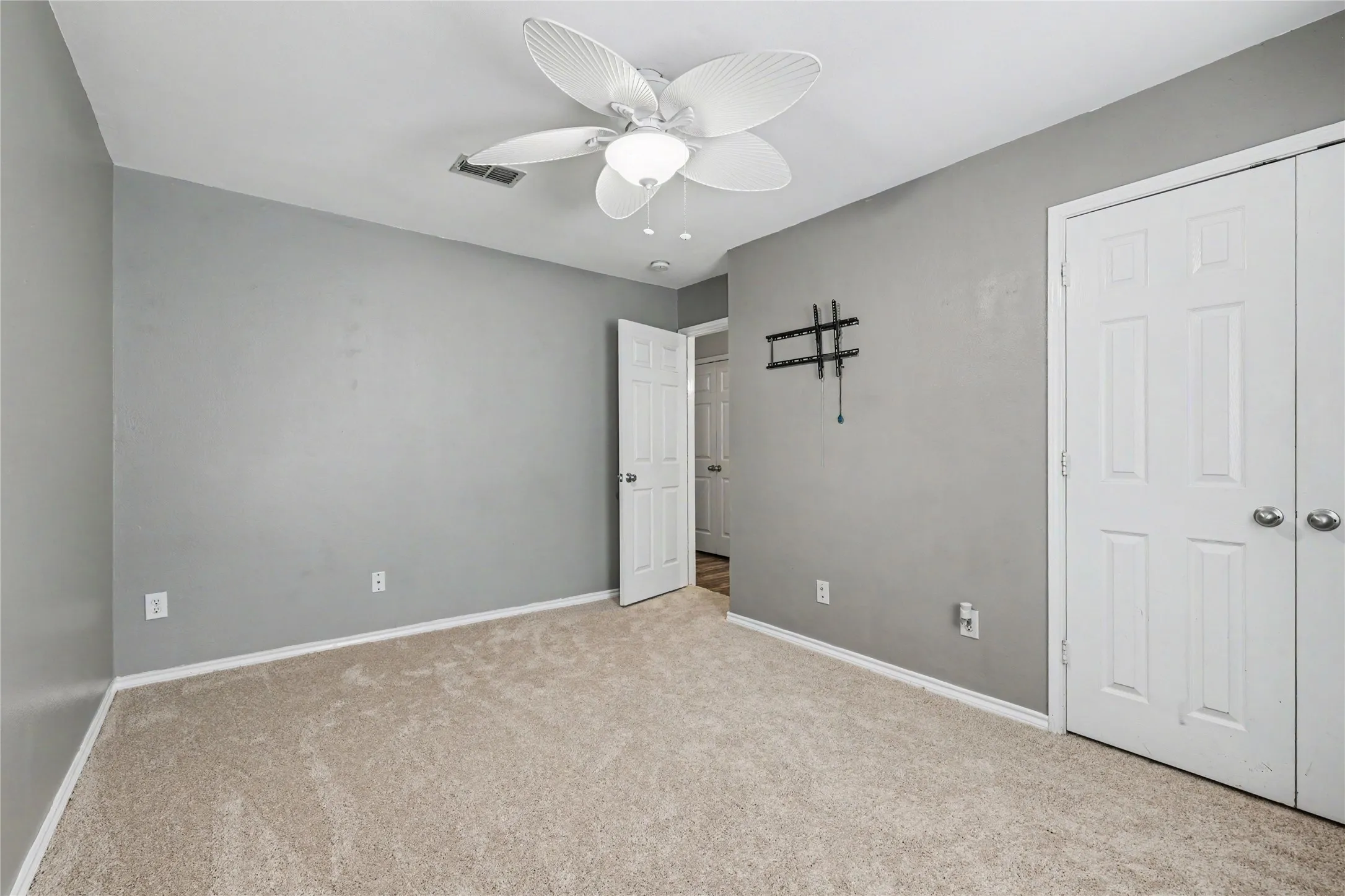 Carpeted room with neutral walls, white trim, and a ceiling fan