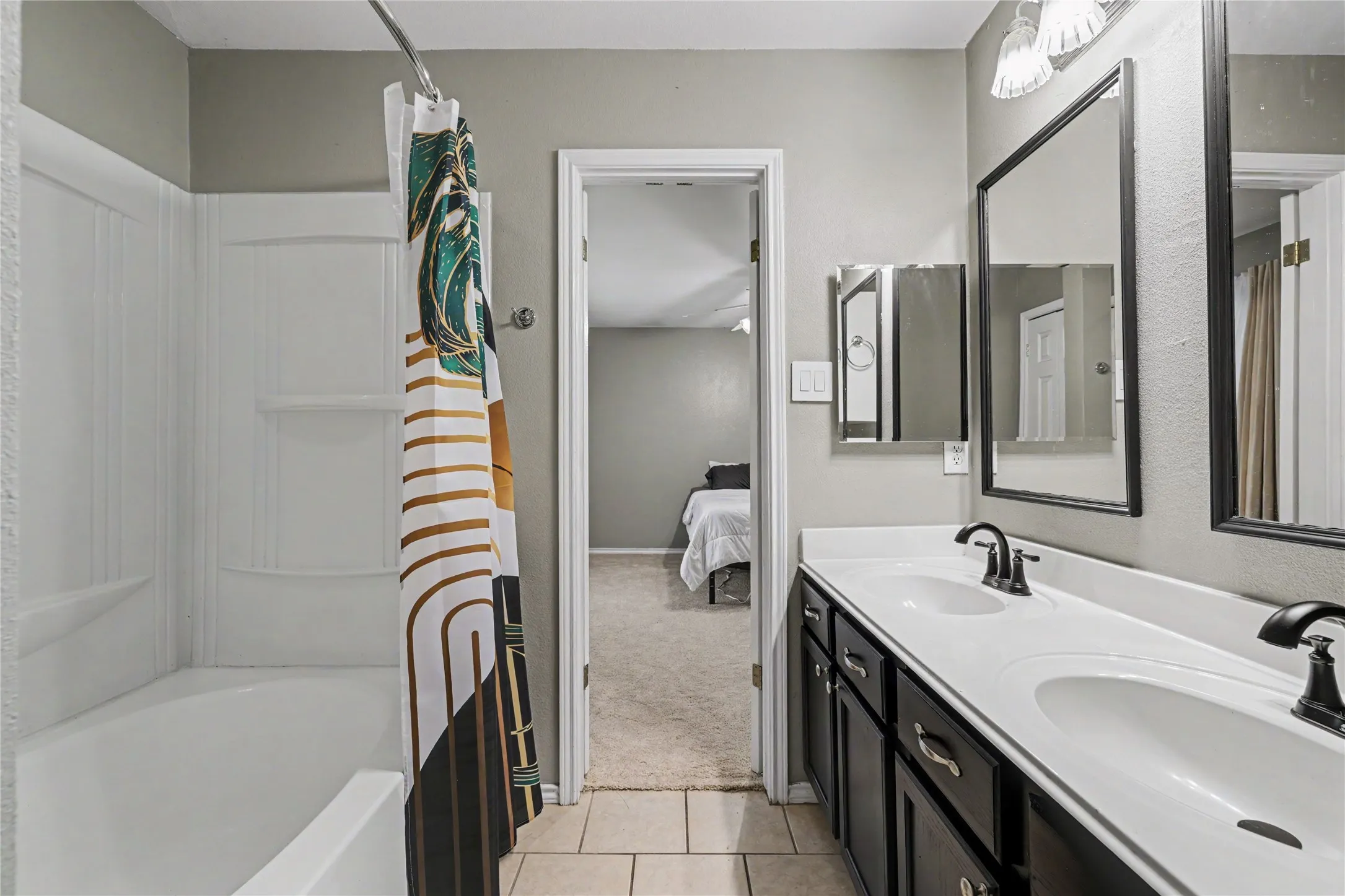 Bathroom featuring a dual-sink vanity with dark cabinetry, white countertops, and black fixtures