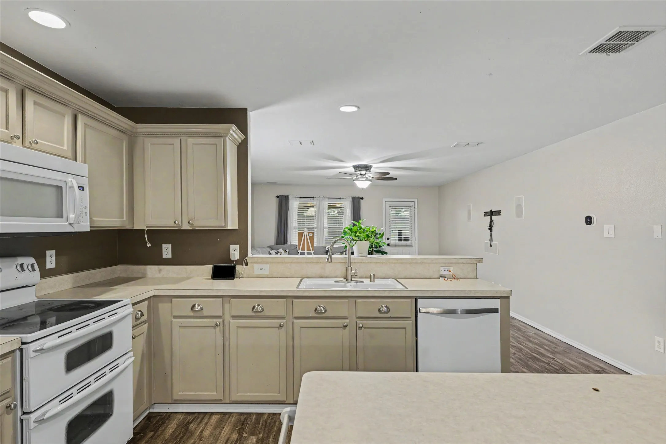 Kitchen featuring light-toned cabinetry, a built-in microwave, and a white electric range with double ovens