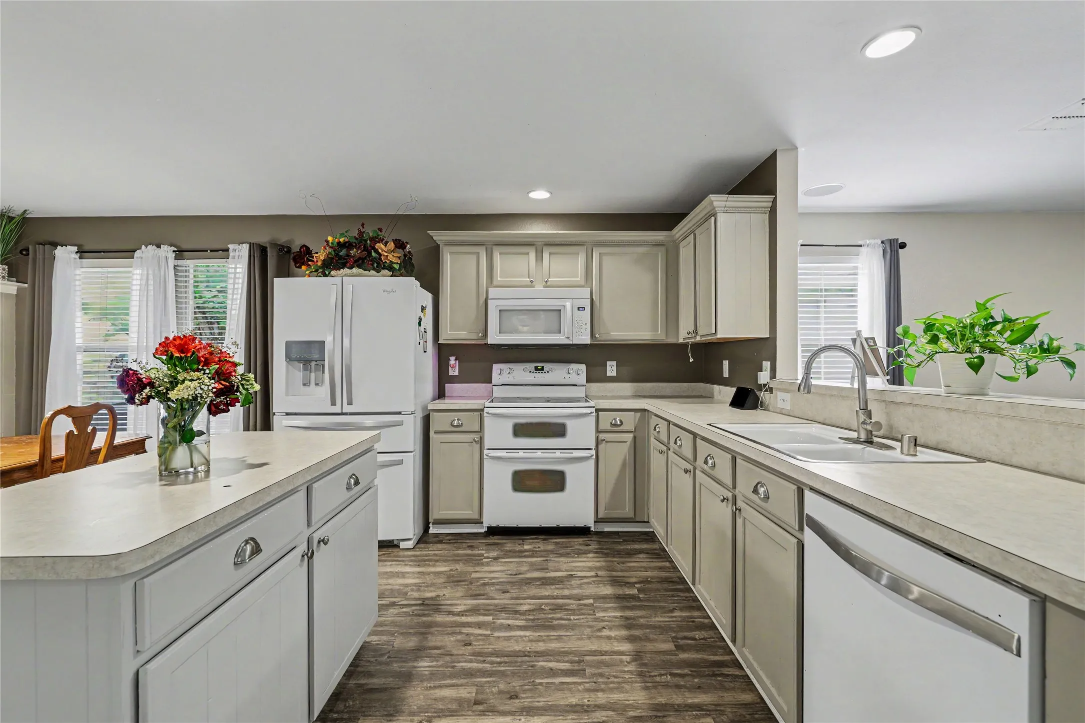 Spacious kitchen featuring an island, extensive countertop space, white cabinetry, a built-in double oven, and wood-finish flooring