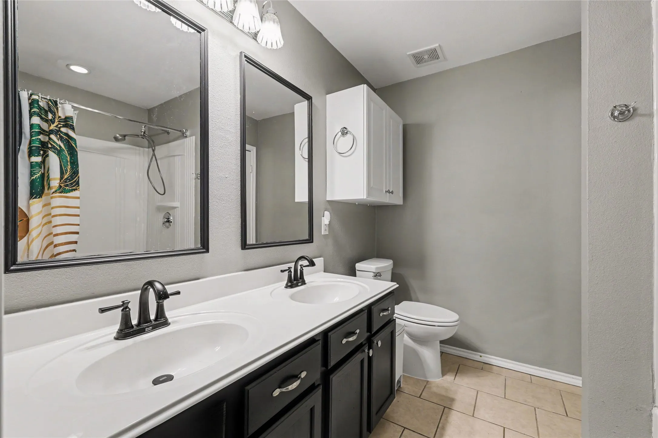 Bathroom featuring a double vanity with dark cabinetry, white countertops, and matte black fixtures