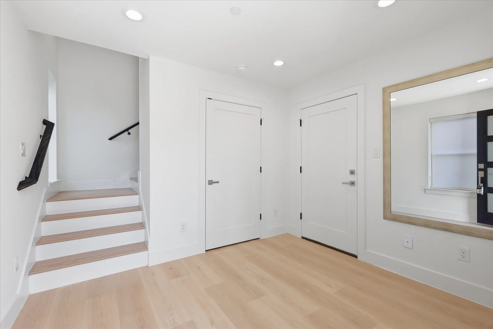 Entry foyer featuring wood-finish flooring, recessed lighting, and a contemporary staircase with a black handrail