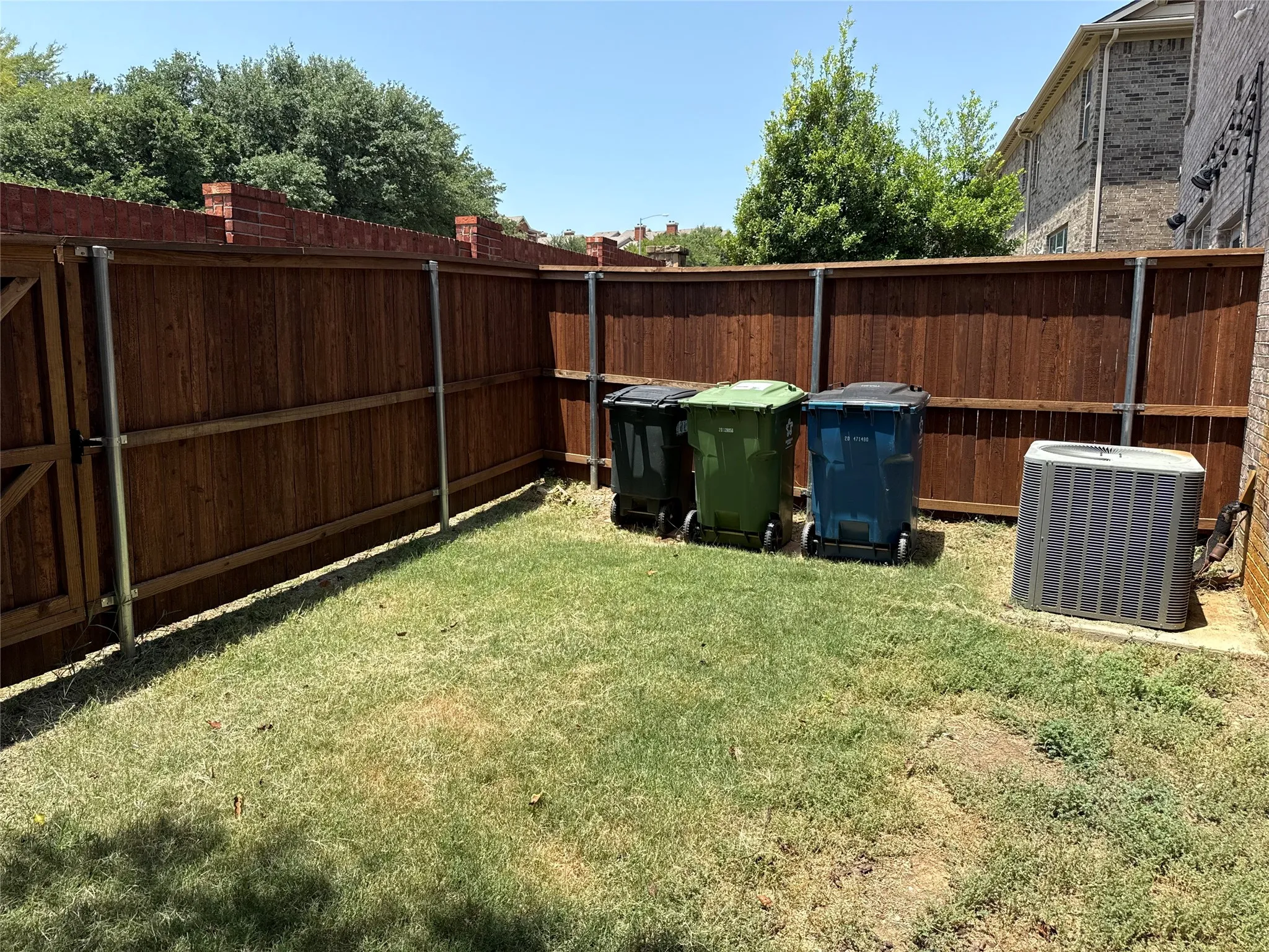 Private outdoor space featuring a wood fence, a side yard, and a brick exterior
